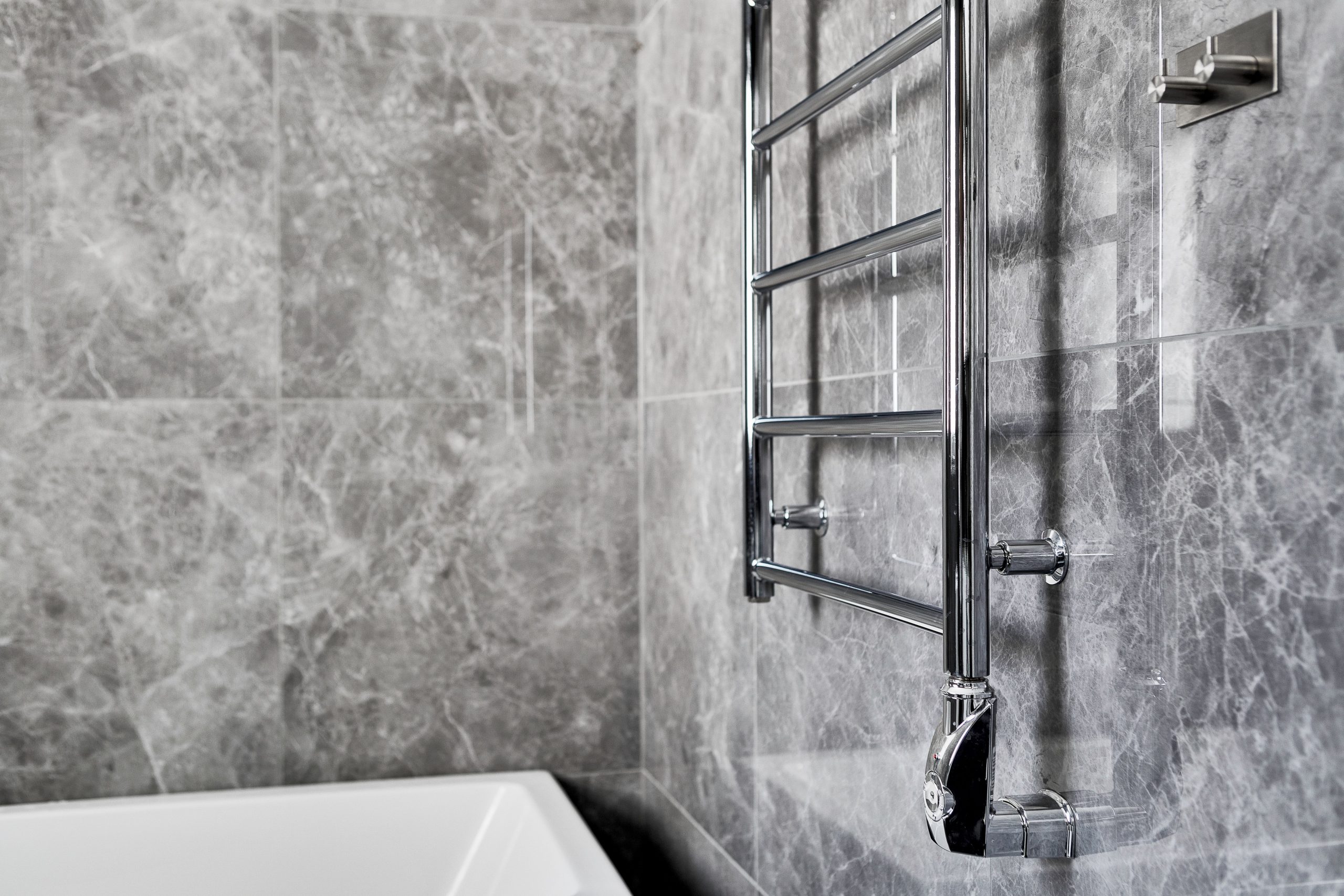 Contemporary bathroom featuring marble walls and a sleek steel towel rail.