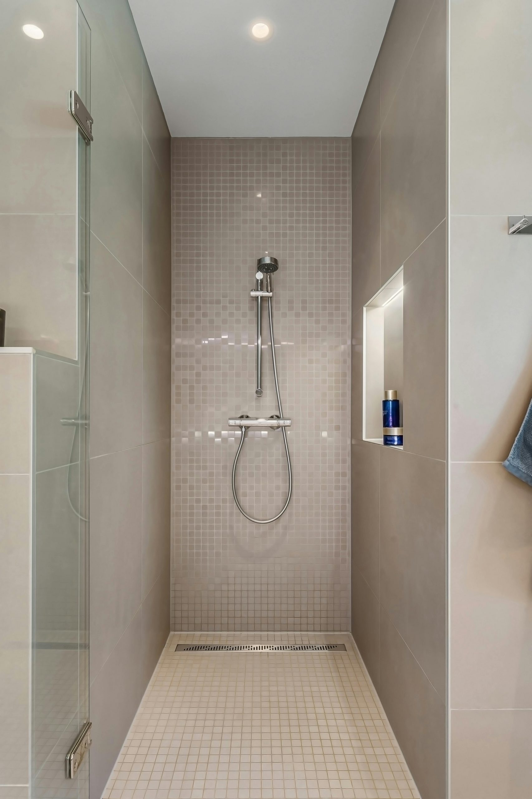 Contemporary shower with glass and tiled surfaces in a minimalist bathroom.