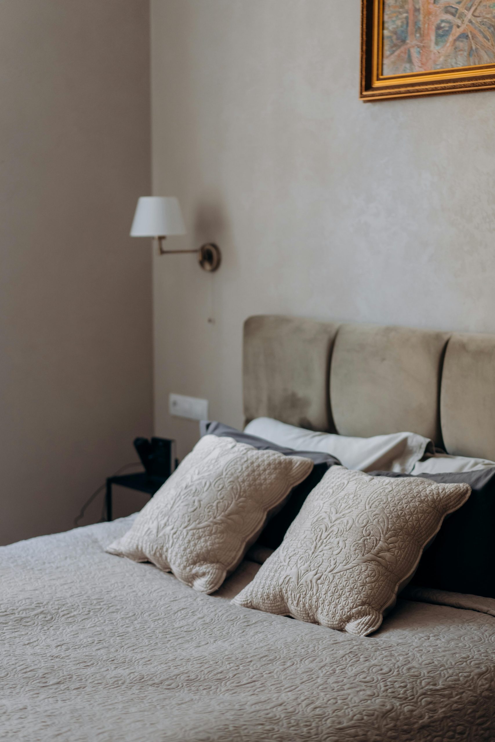 Cozy and elegant bedroom interior showcasing minimalist design with a focus on bedding and wall art.