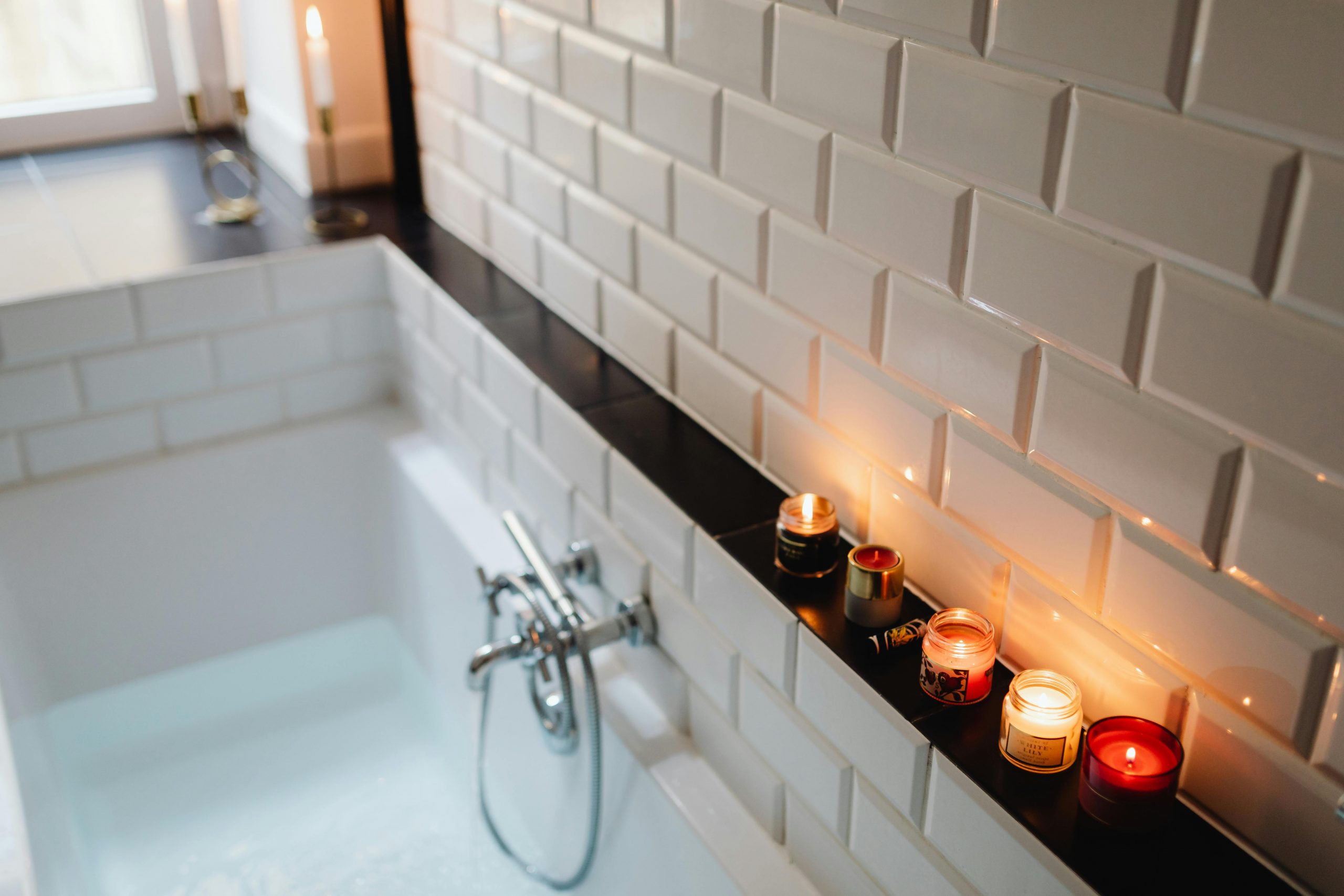 Cozy bathroom setting with candles and a filled bathtub, ideal for relaxation.