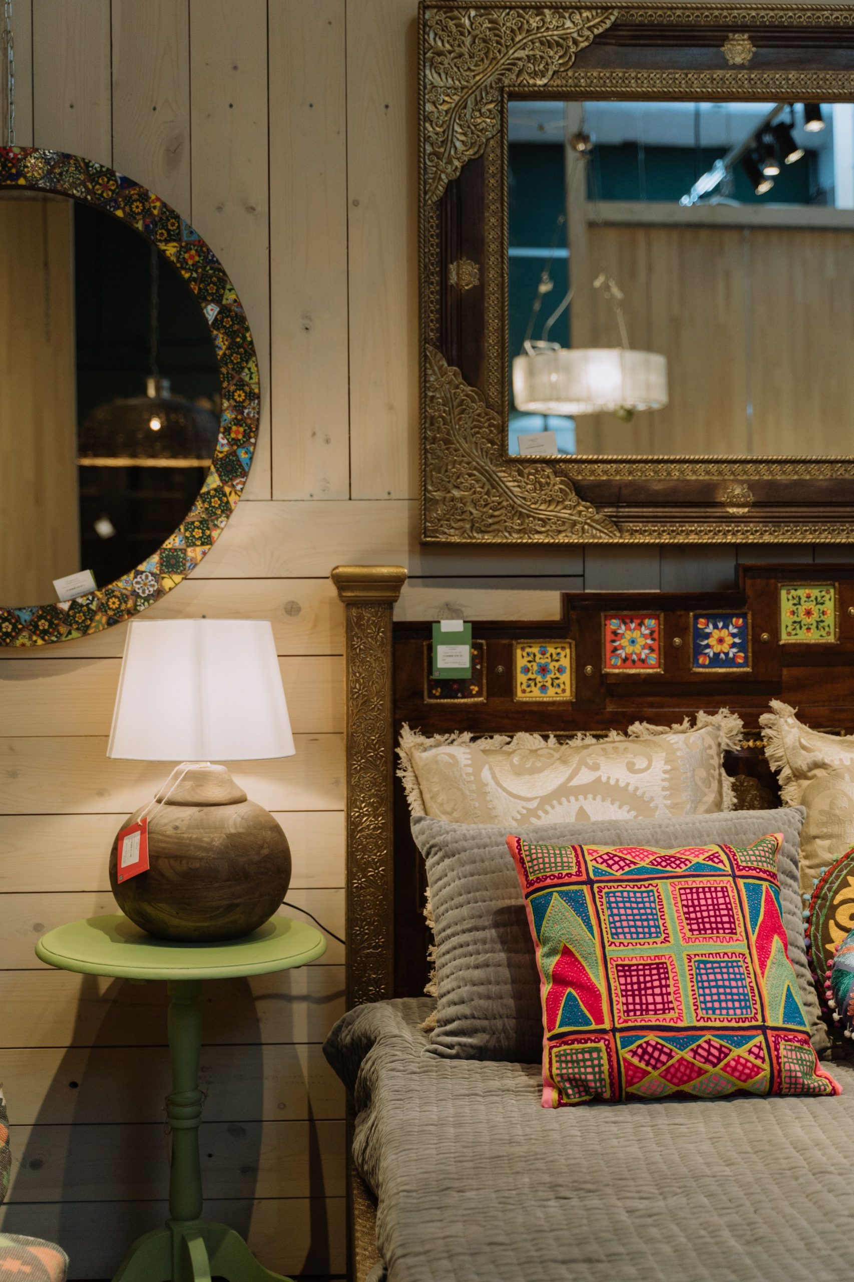 Cozy bedroom featuring bohemian decor with ornate mirrors, colorful cushions, and soft lighting.