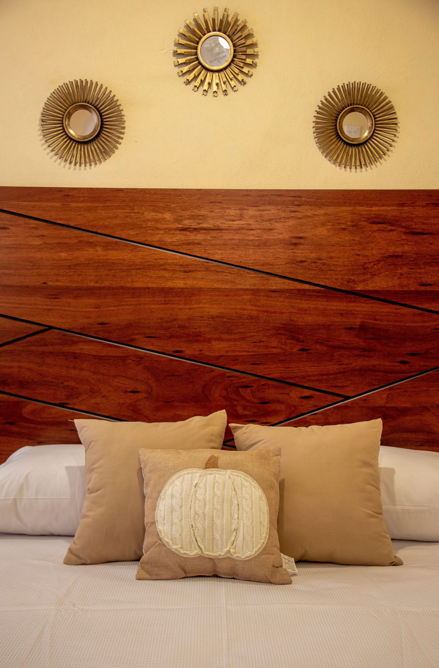 Cozy bedroom with decorative pillows against a modern wood headboard.