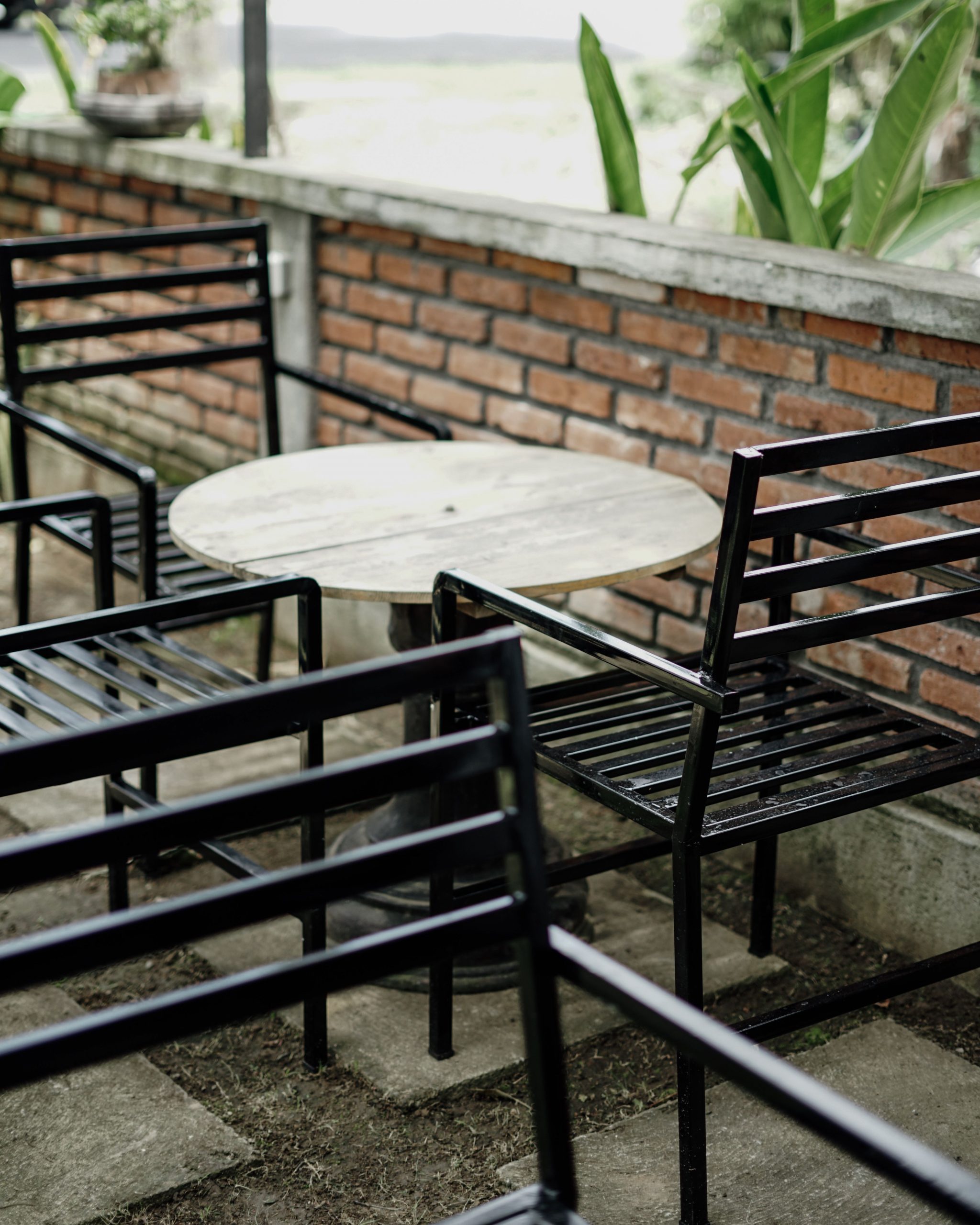 Cozy outdoor patio with black metal chairs and round wooden table, inviting ambiance.