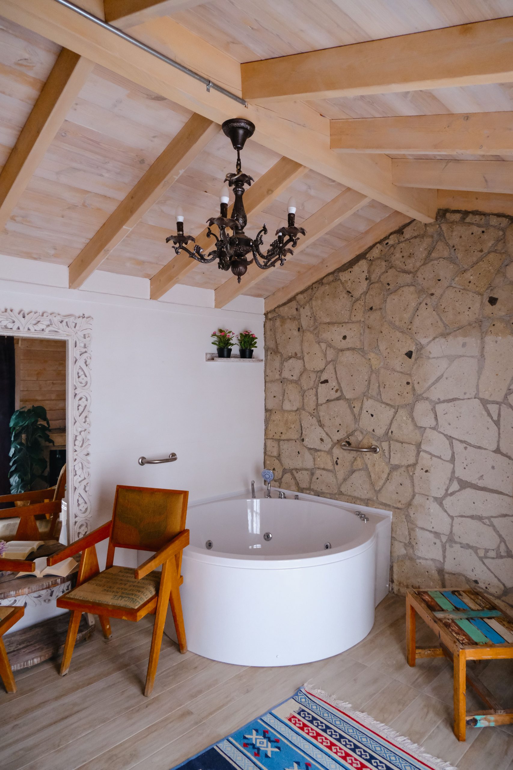 Cozy rustic bathroom design featuring a round bathtub and stone wall with vintage decor.