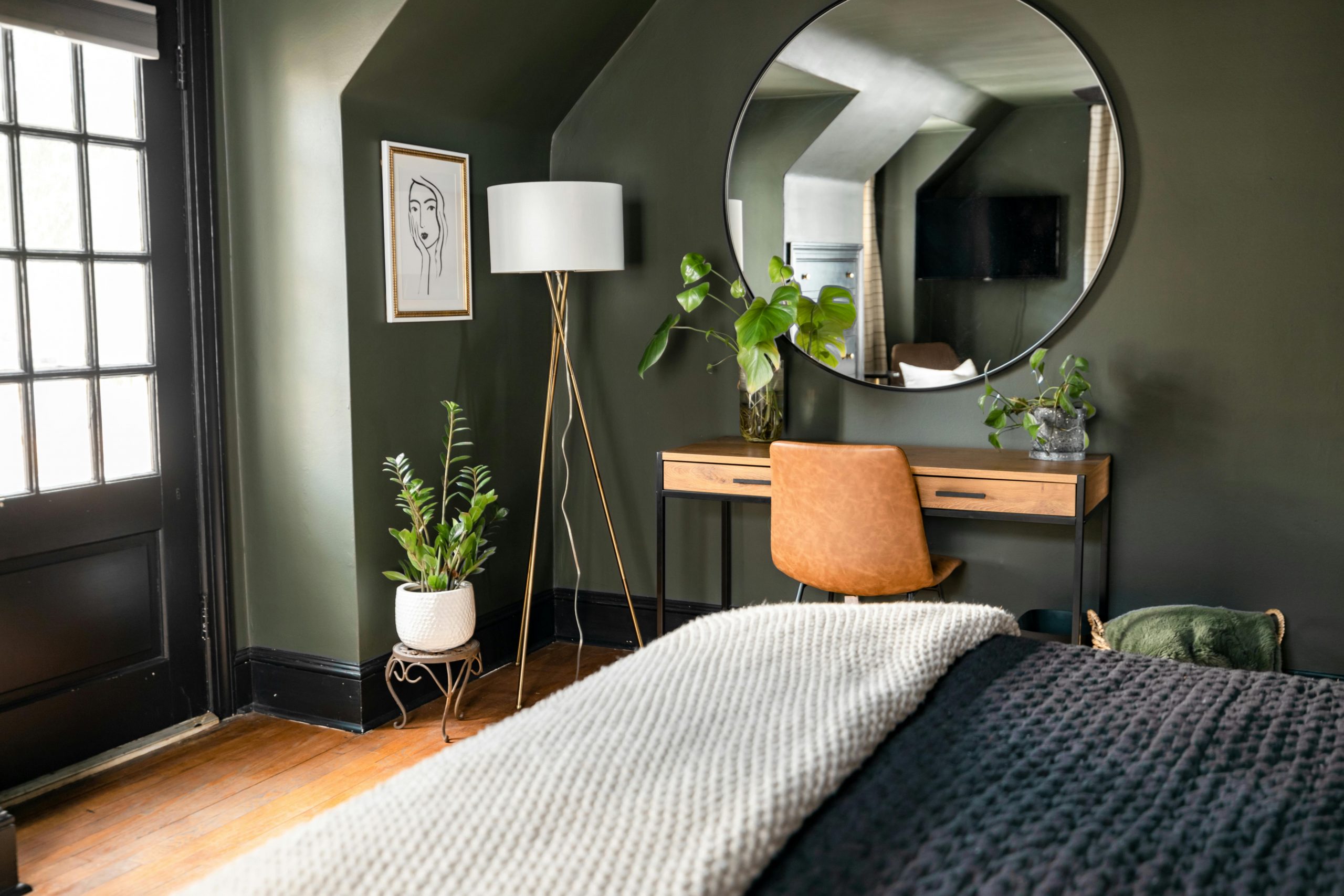 Elegant and cozy bedroom featuring green walls, modern decor, and natural lighting for a peaceful ambiance.