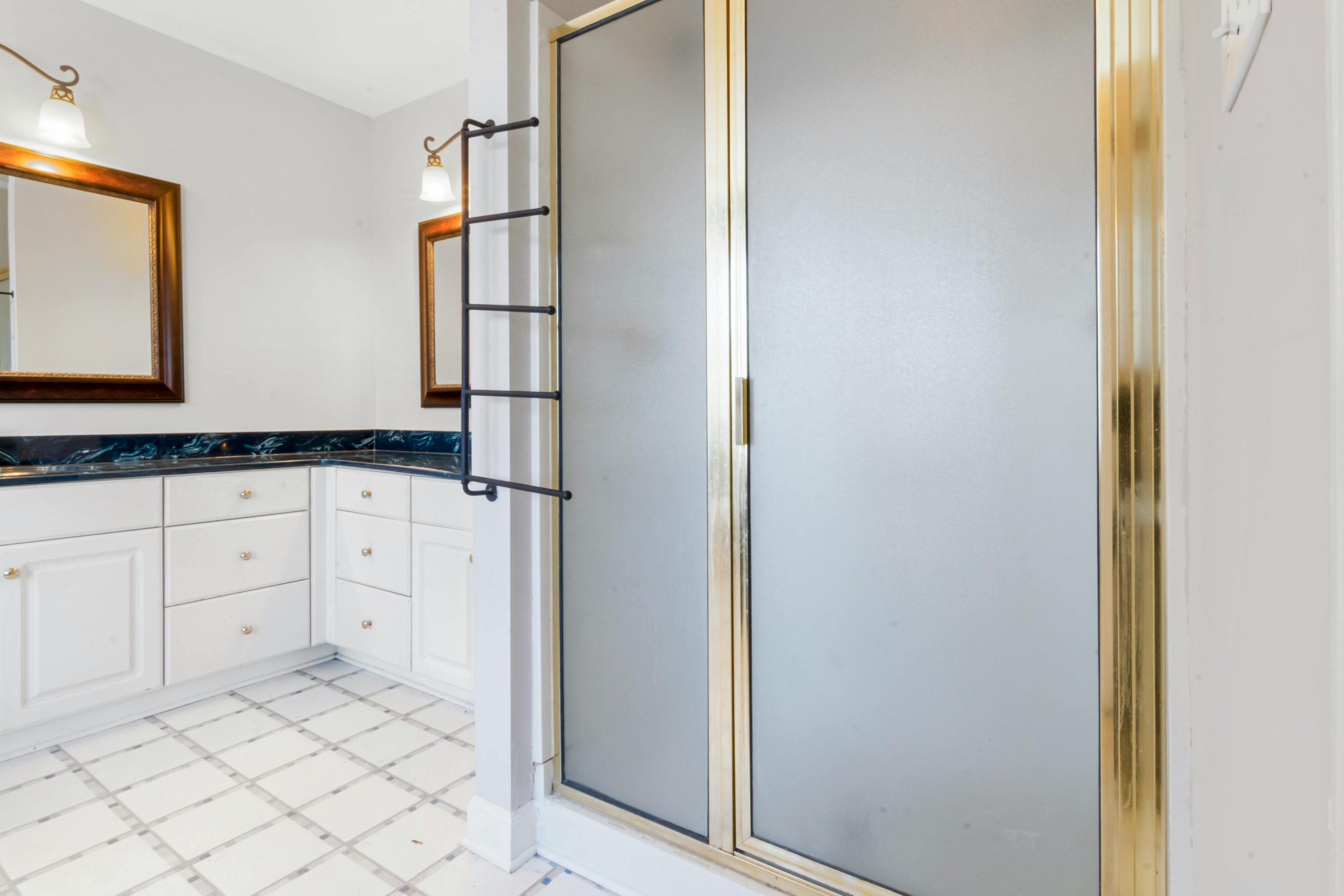 Elegant bathroom featuring a shower with gold trim and marble countertops, highlighting modern interior design.