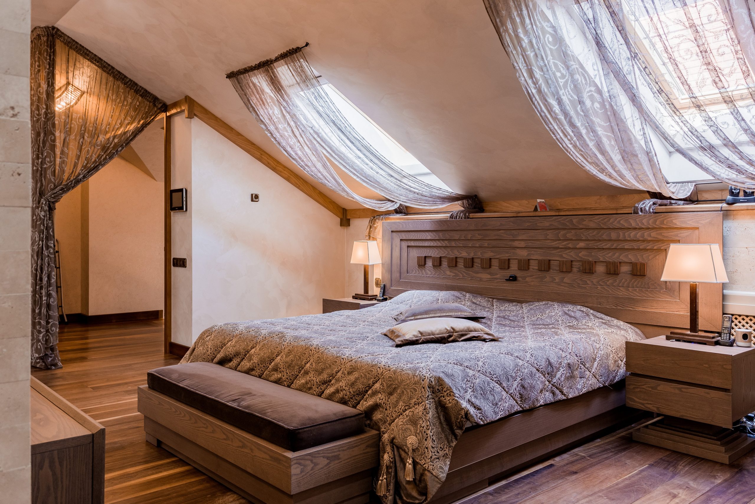 Elegant bedroom interior showcasing luxurious bedding, wooden accents, and draped curtains.