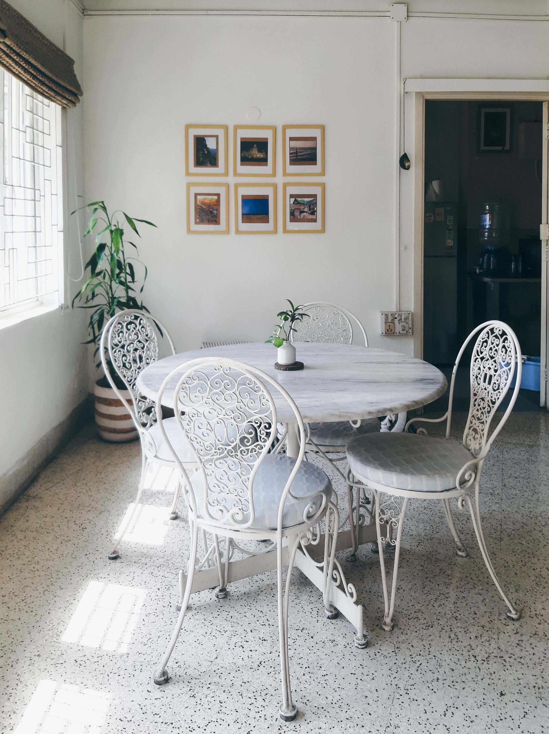 Elegant dining setup with vintage metal chairs and round table in a sunlit room in Kolkata, India.
