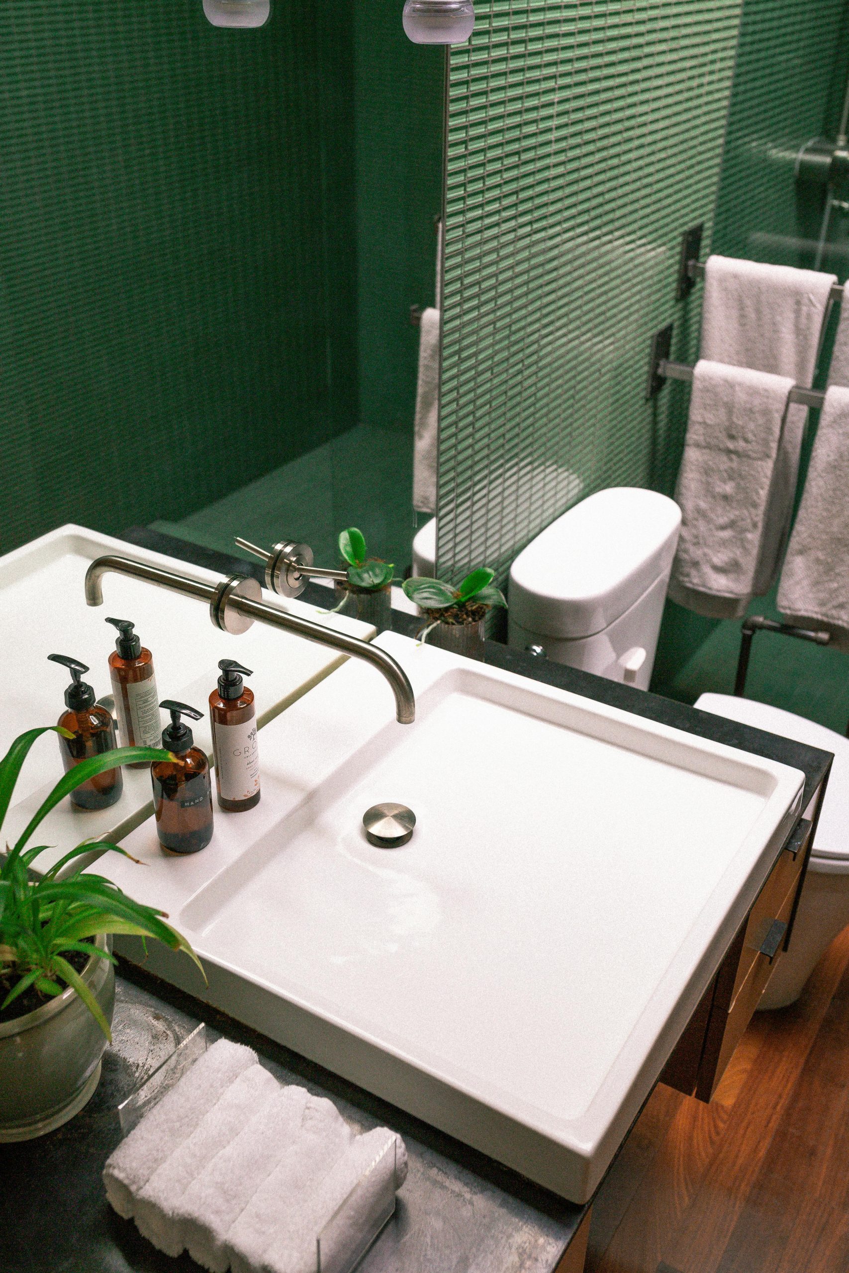Elegant green bathroom features modern sink and stylish fixtures.