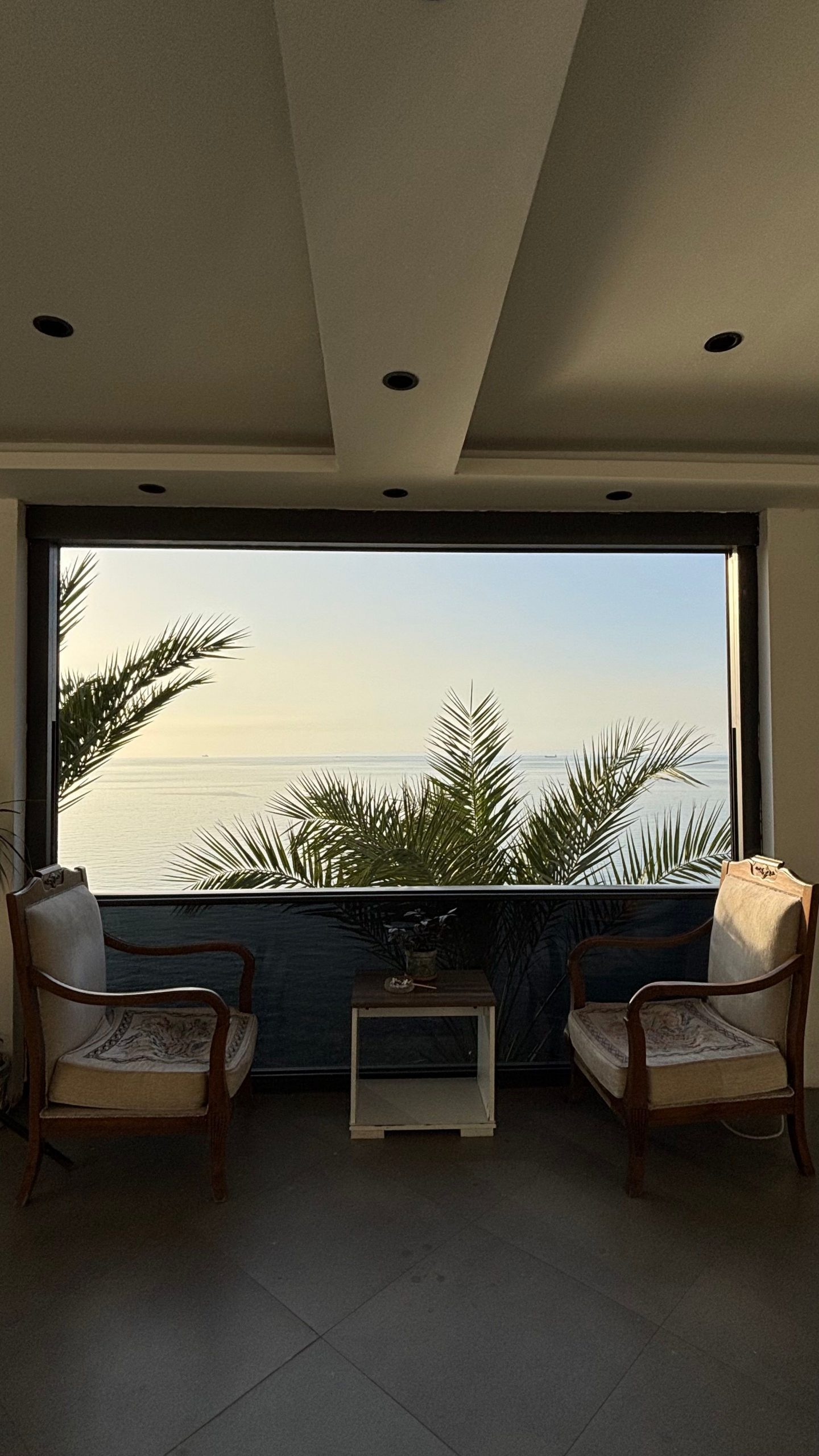 Elegant lounge with palm view over the ocean at sunset, serene and inviting.