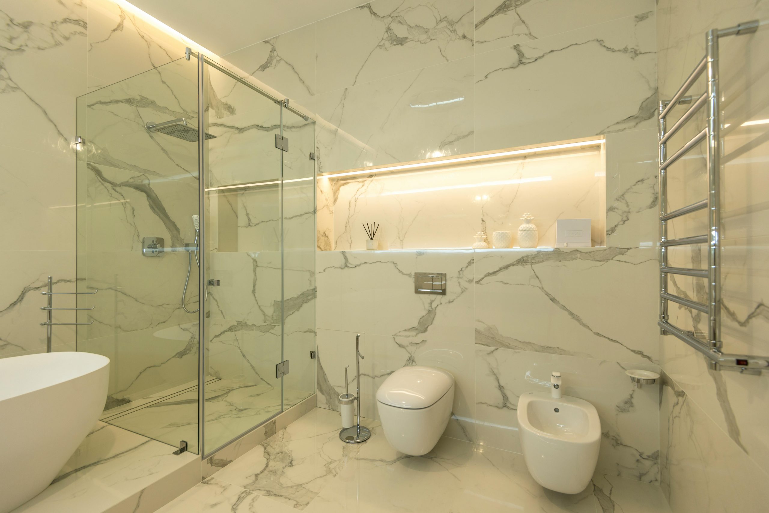 Elegant luxury bathroom featuring marble walls, a glass shower, and modern fixtures.