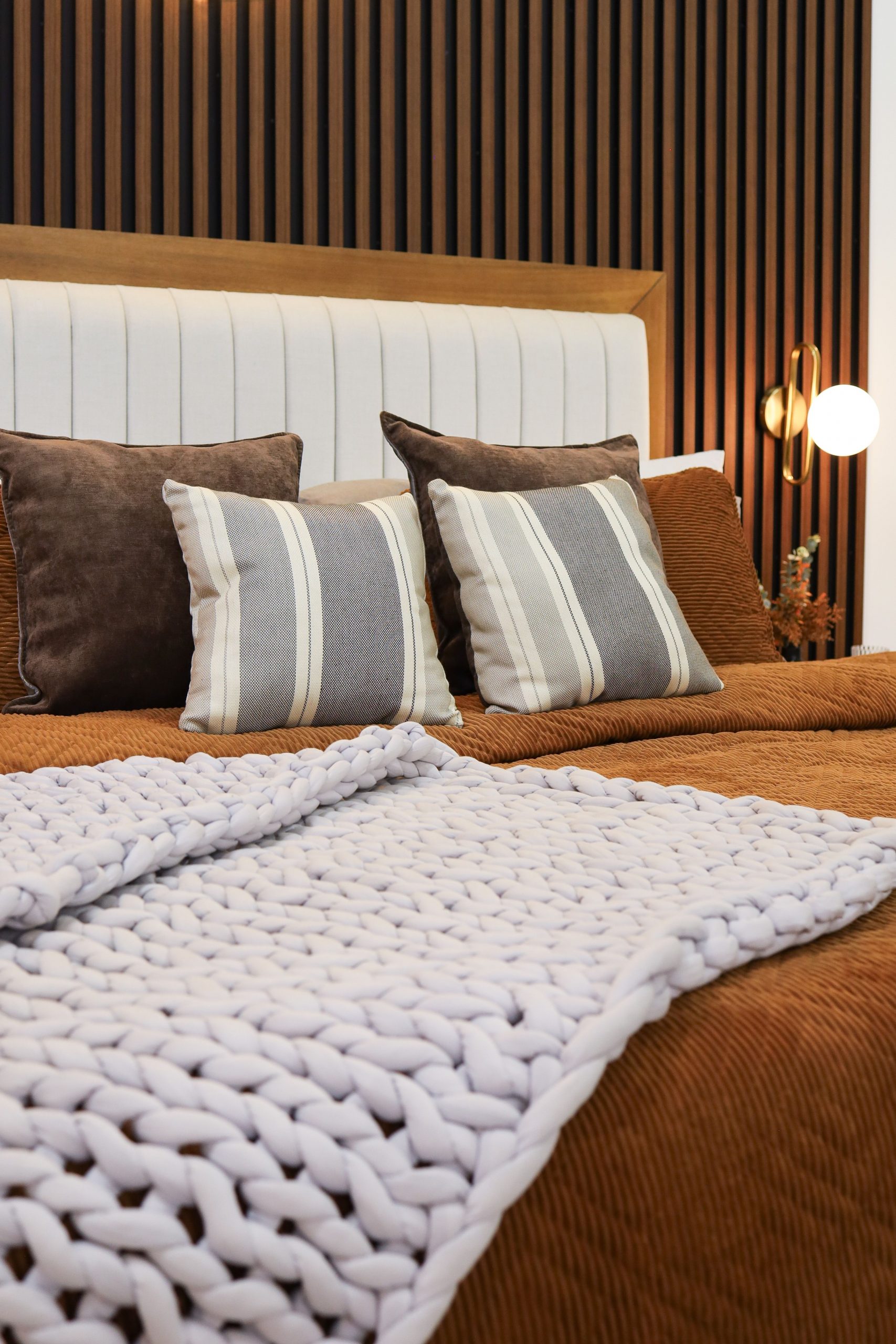 Elegant modern bedroom featuring striped pillows and a woven blanket.