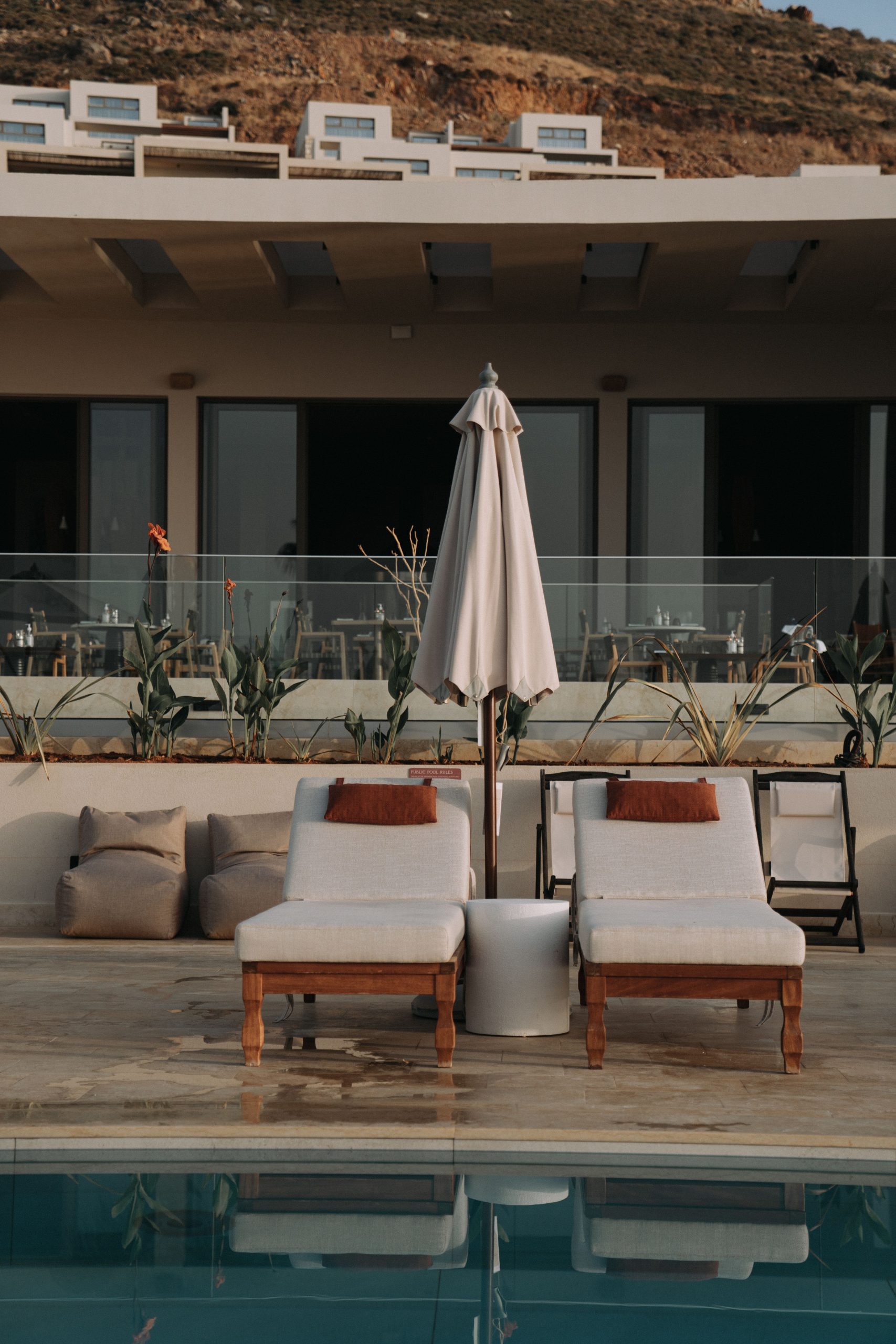 Elegant poolside setup with sun loungers and an umbrella, perfect for relaxation in a modern resort.