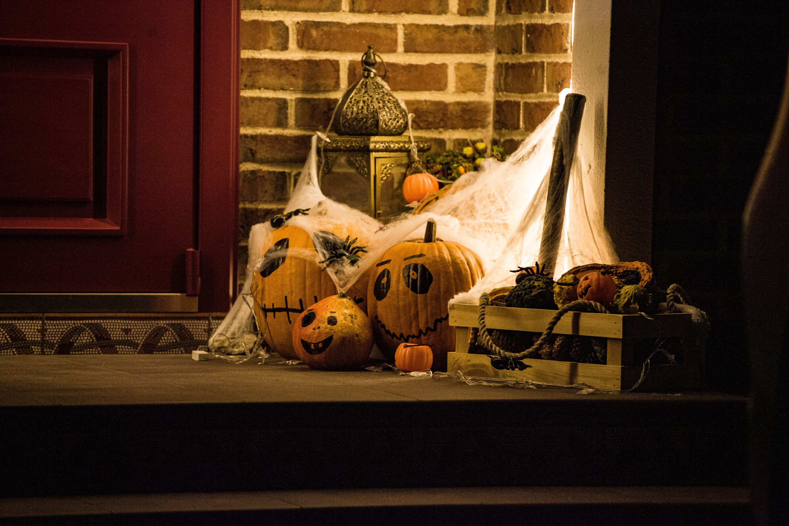 Festive Halloween decor featuring carved pumpkins and cobwebs at a doorstep.