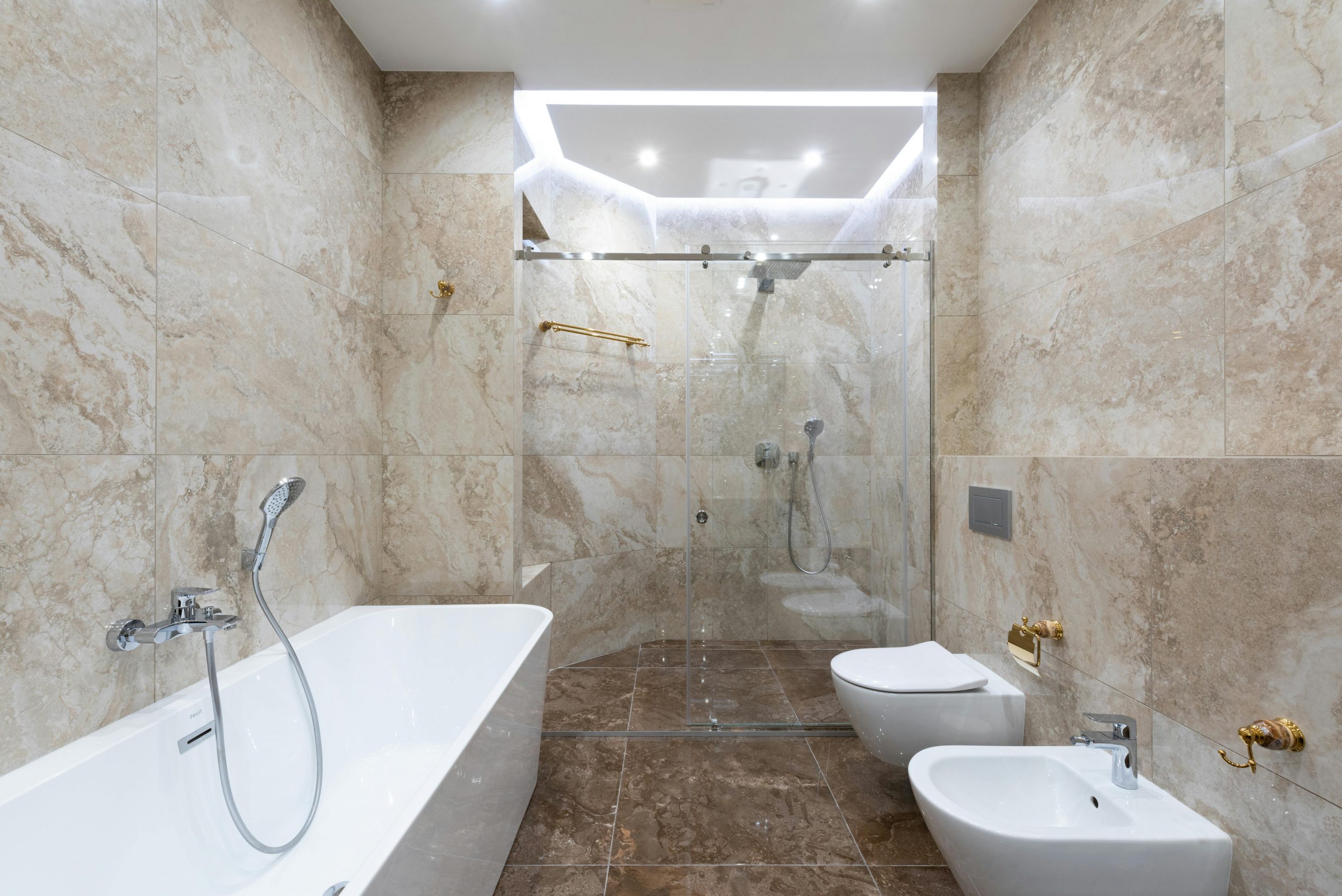 Interior of contemporary bathroom with marble walls and comfortable shower cabin under bright light of lamp
