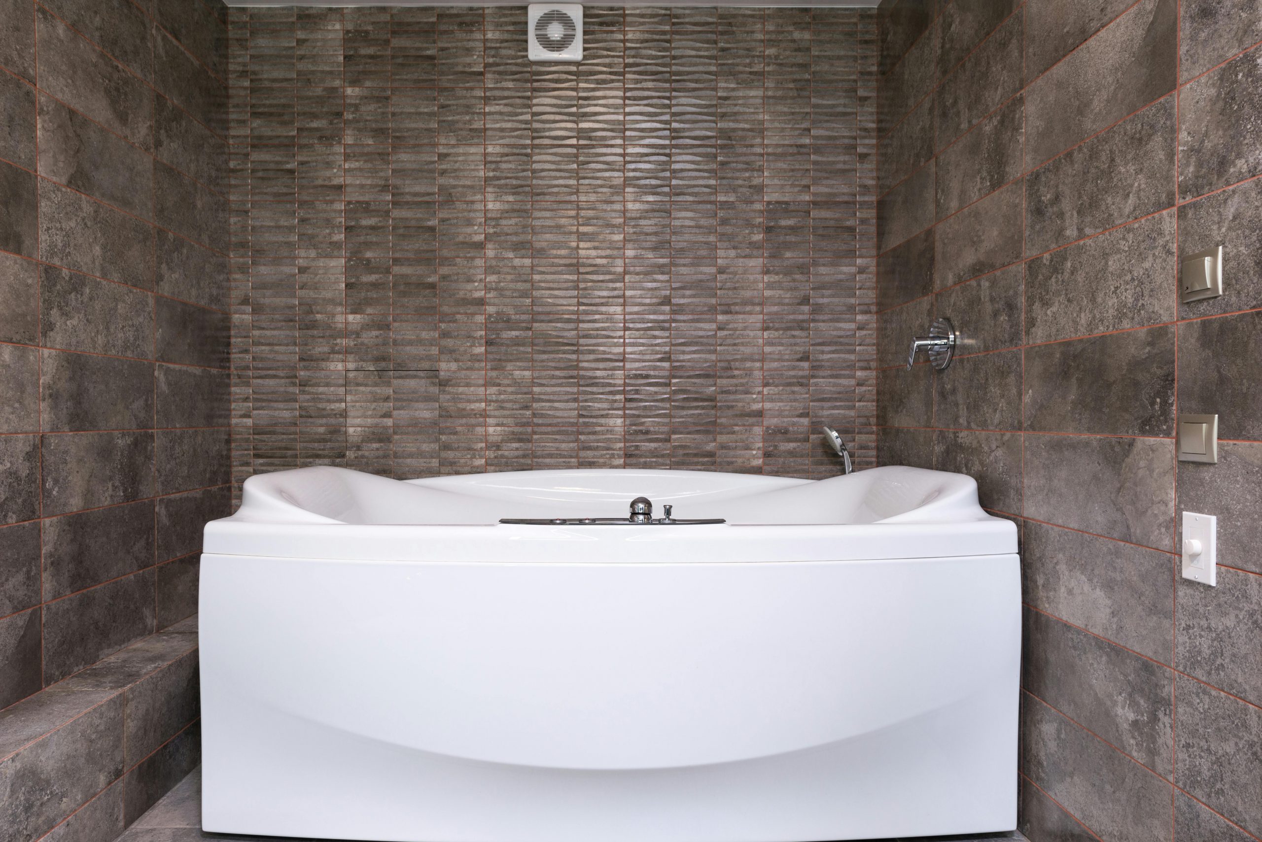 Interior of contemporary bathroom with white hot tub and metal faucet and shower