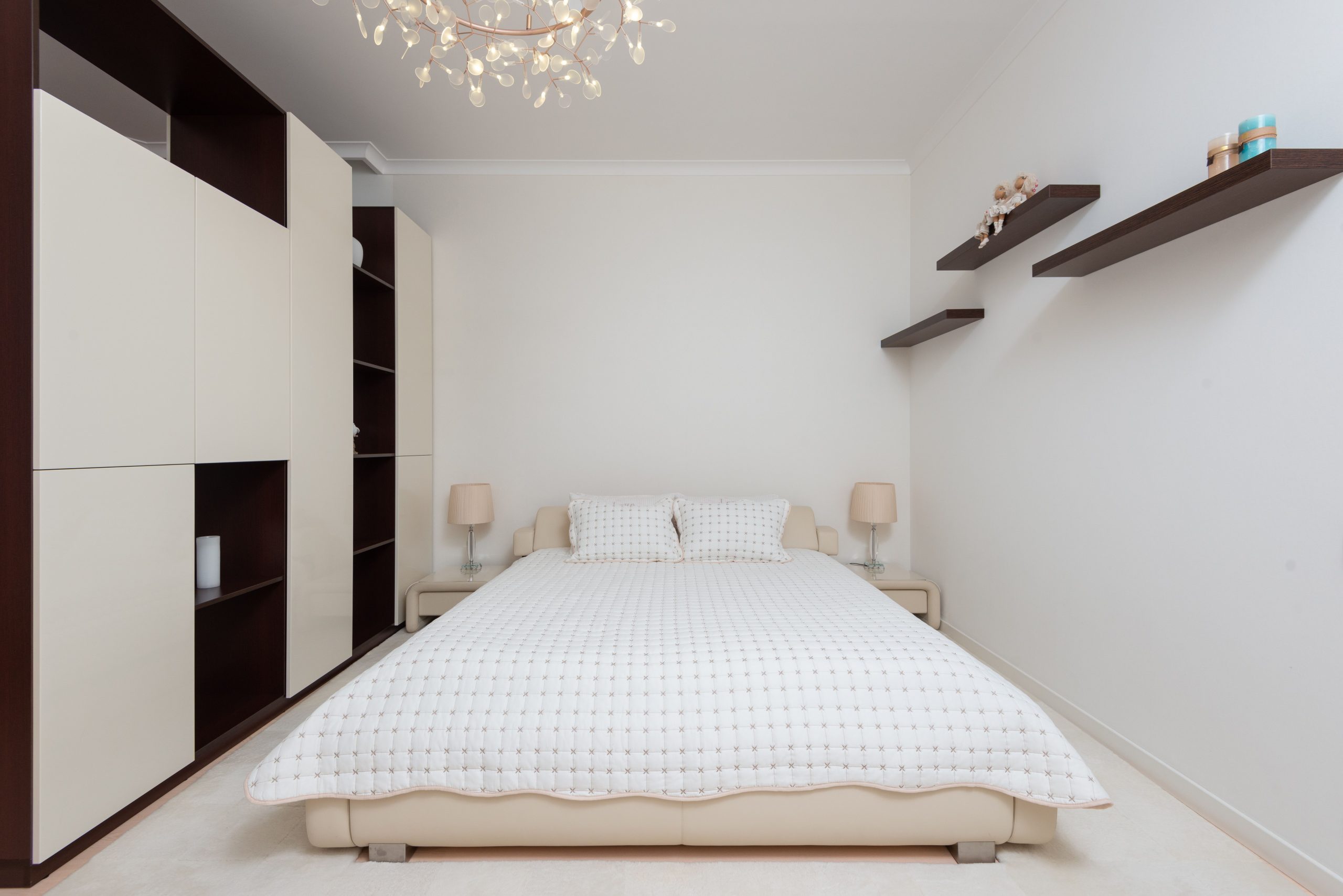 Interior of contemporary large bedroom with black shelves and bed with soft cushions