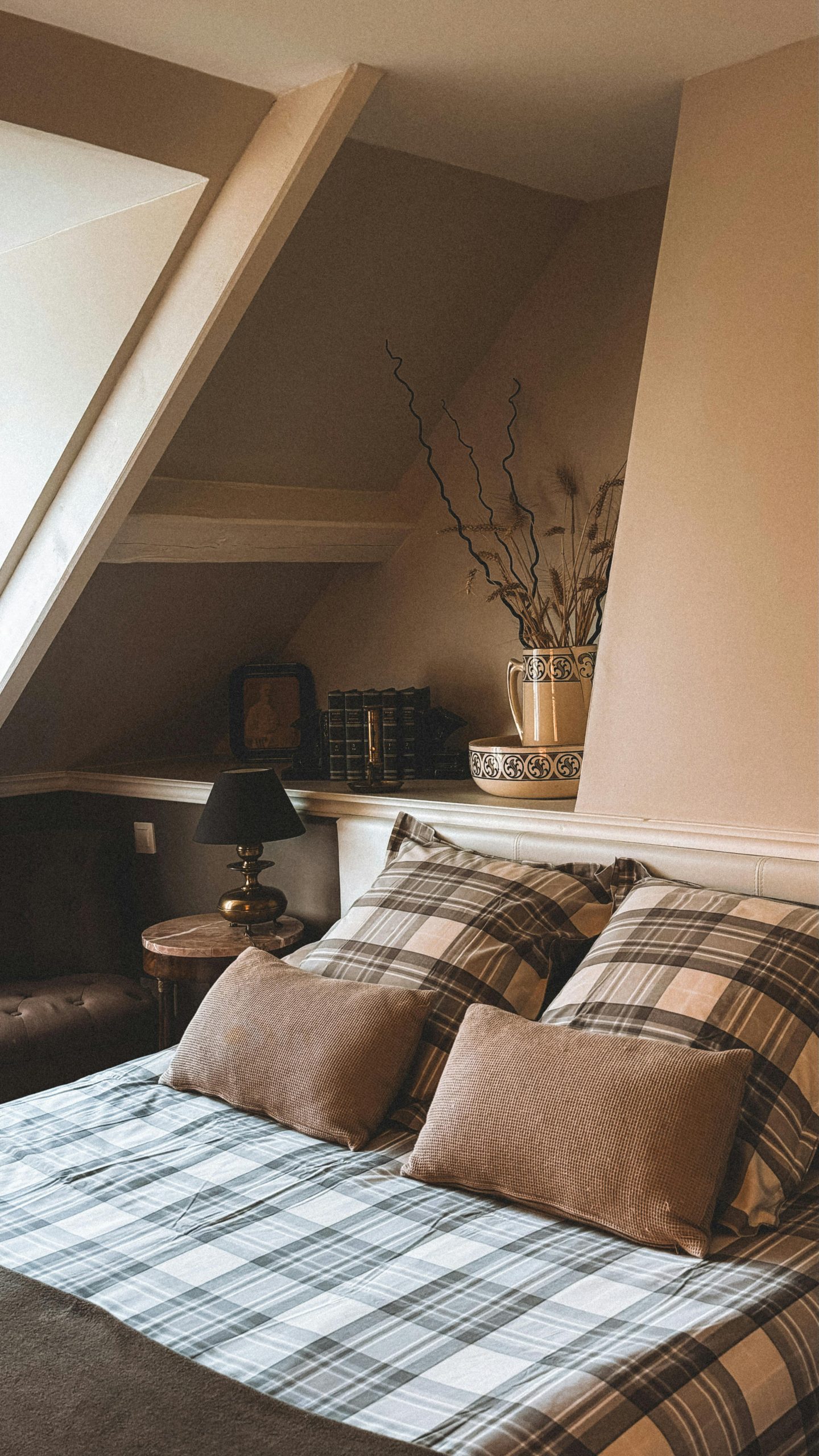 Inviting attic bedroom with boho style decor and plaid bedding in Andorra.