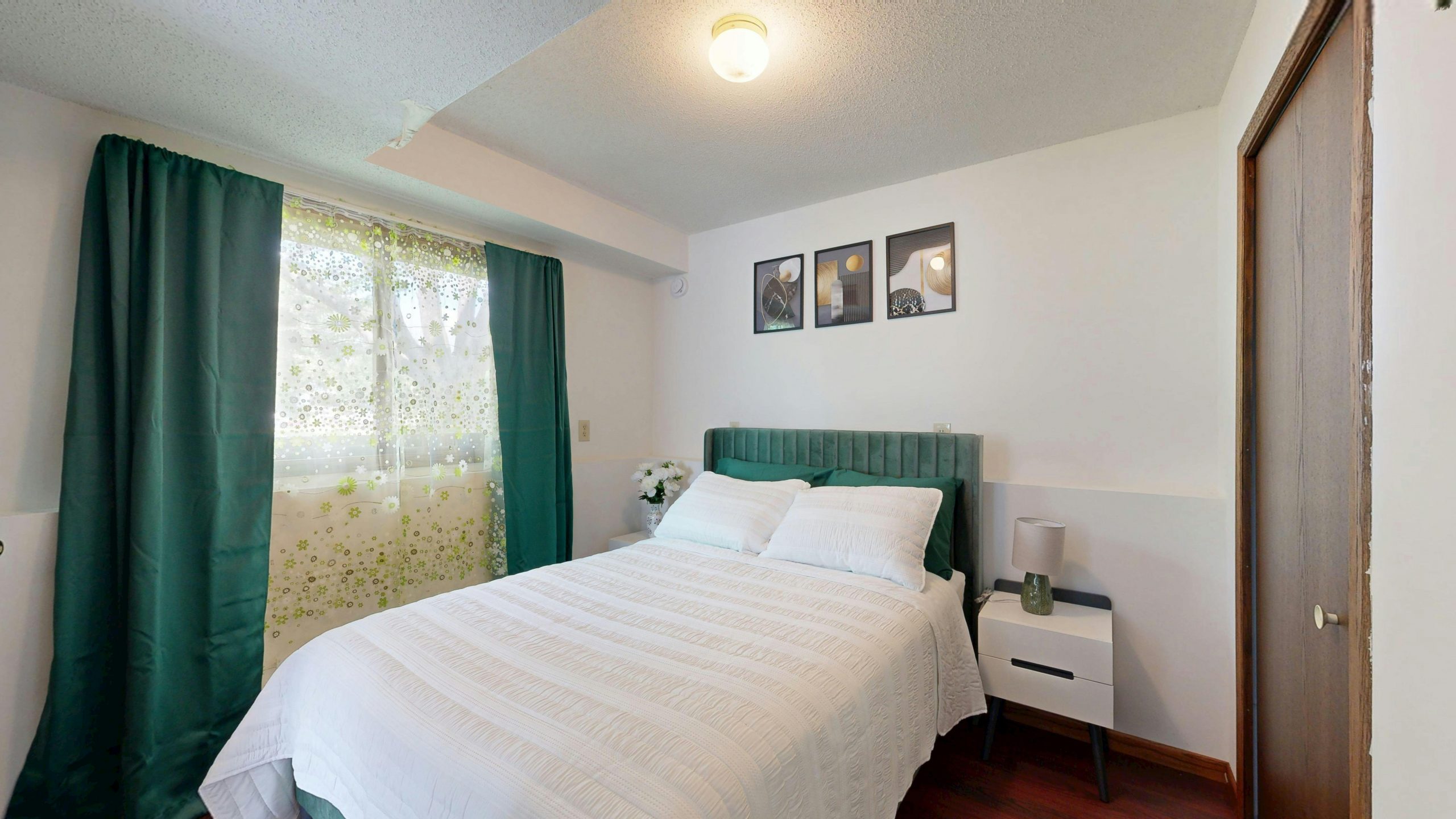 Inviting bedroom with green decor elements, natural lighting, and modern art.