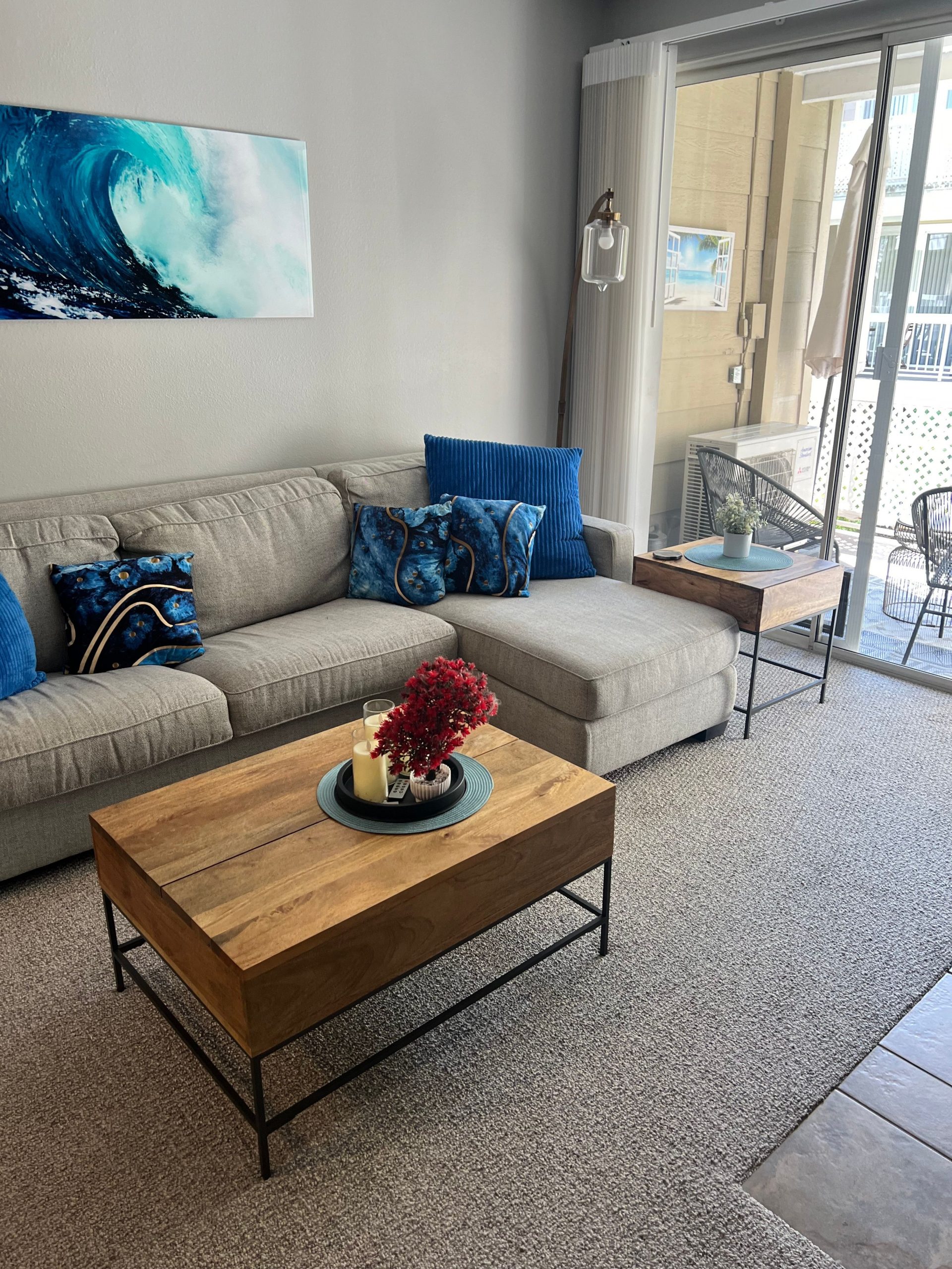 Inviting living room with gray sofa and blue decor accents, featuring a wave painting.