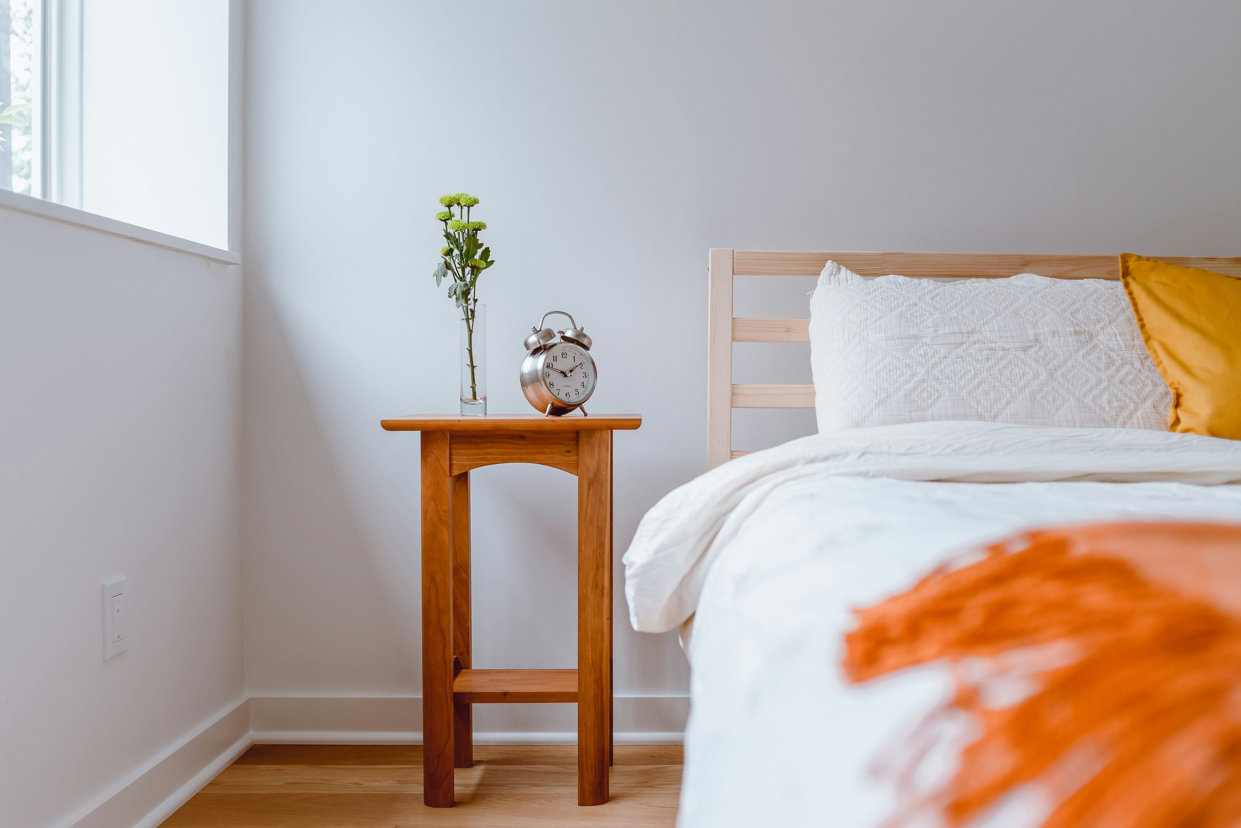 Light and Airy Bedroom with Old clock on Nightstand and colorful pillow