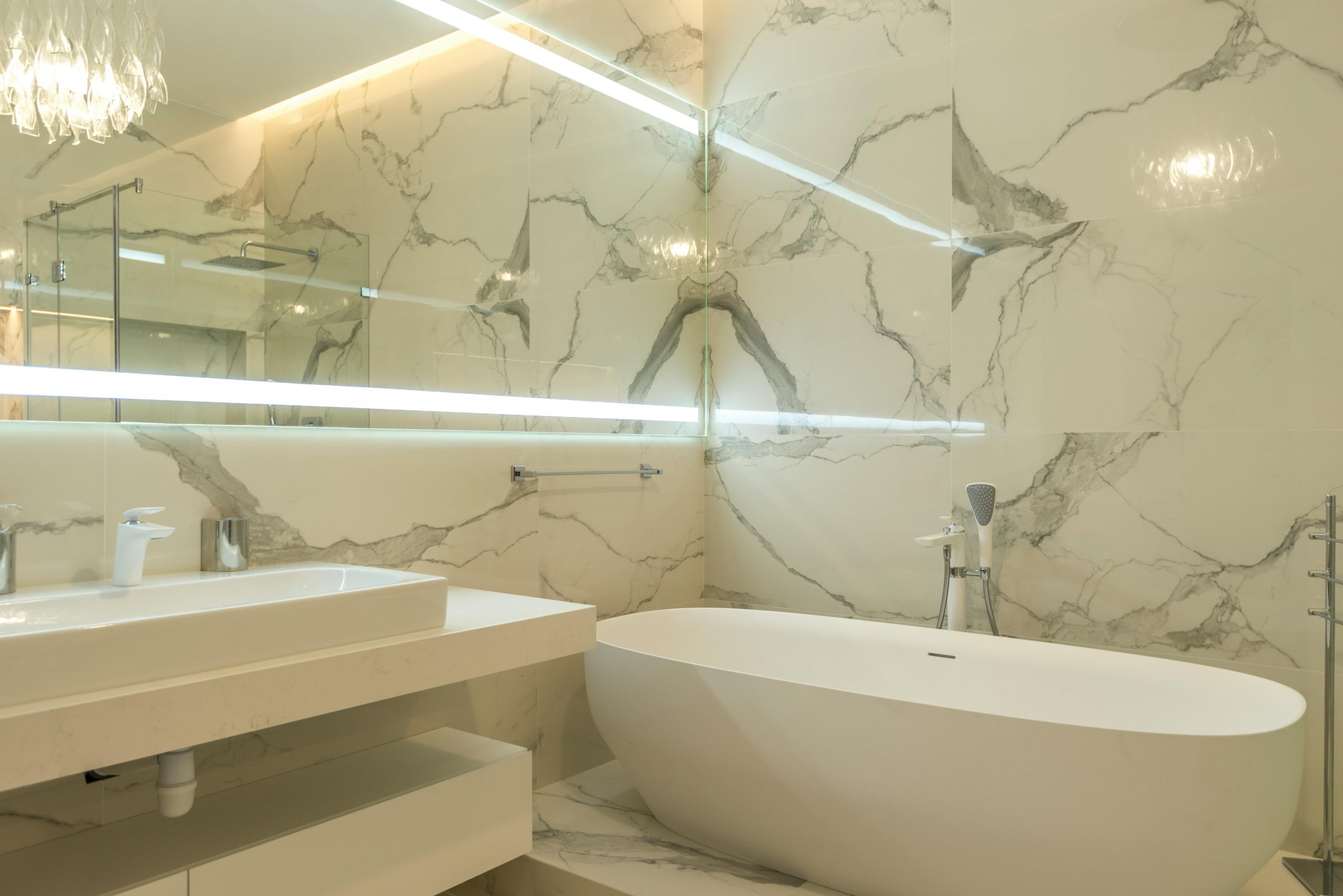 Luxurious bathroom interior featuring marble walls and a sleek modern design with oval bathtub.