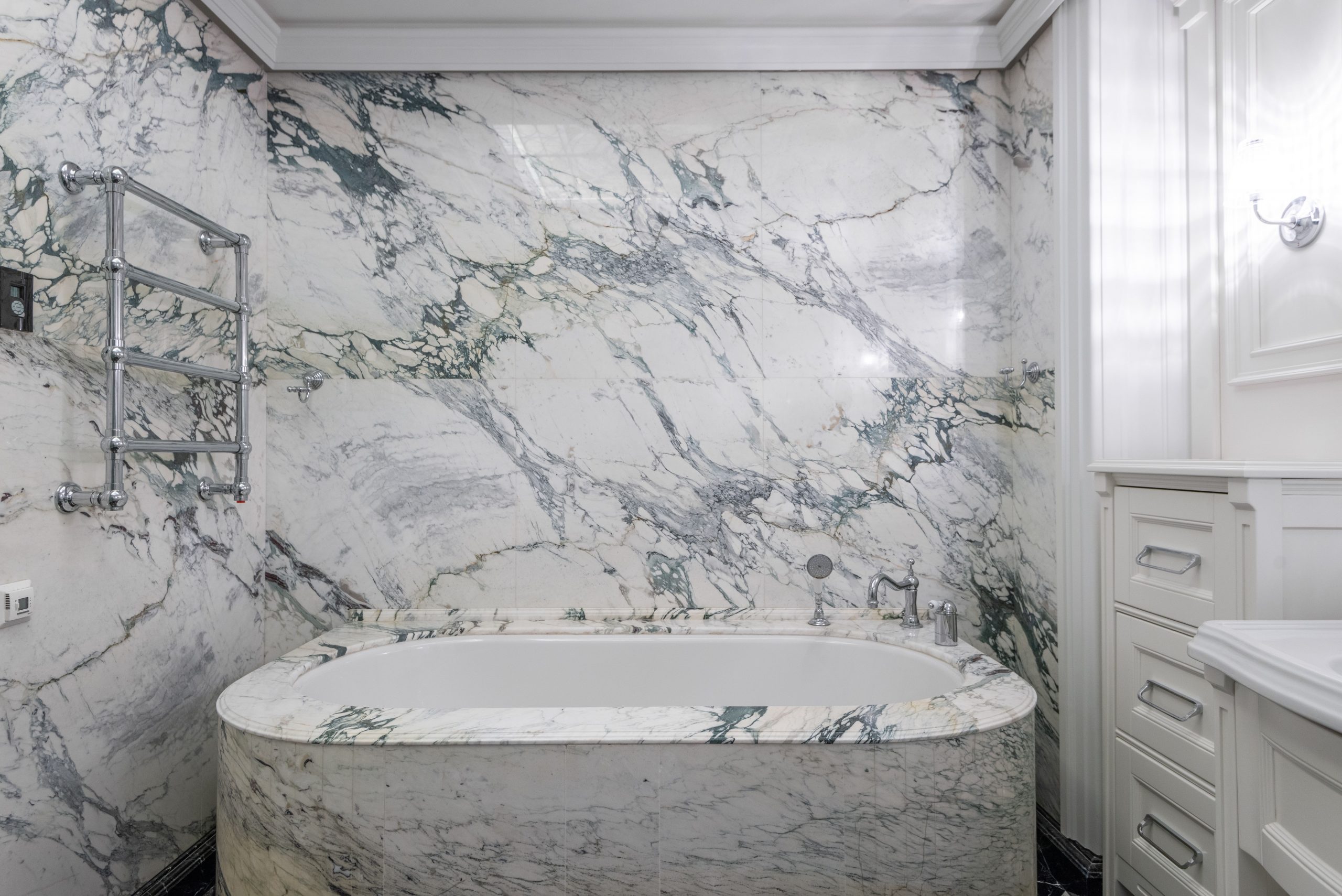 Luxurious modern bathroom with marble tub and wall, featuring elegant design elements.