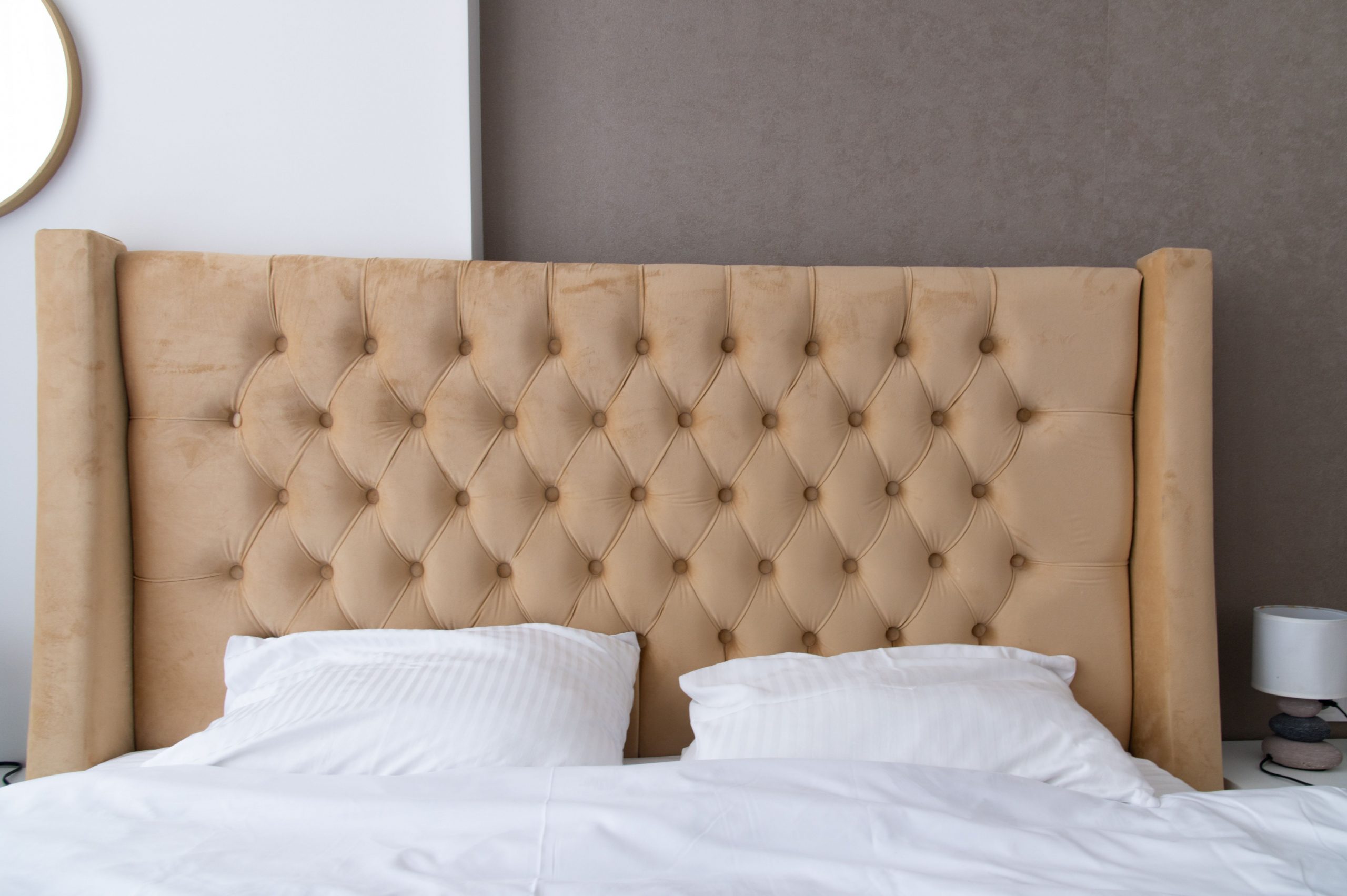 Luxurious tufted bed headboard in a stylish, modern bedroom setting with neutral tones.