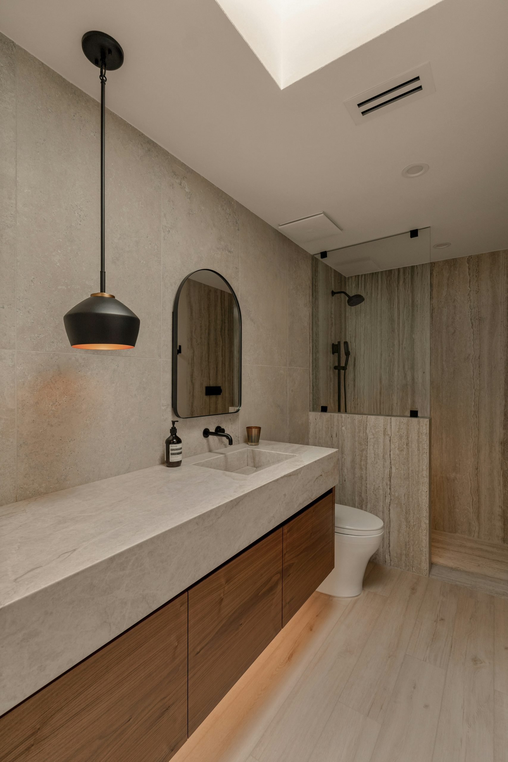 Luxury bathroom renovation with a stone vanity, floating cabinets, and walk-in shower. Soft ambient lighting and modern design create a high-end, minimalist aesthetic.