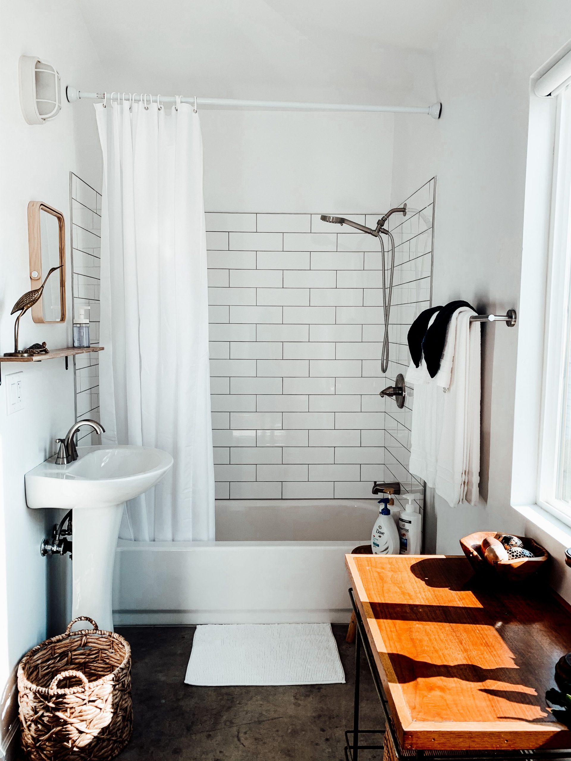 Modern bathroom featuring white subway tiles, a pedestal sink, and warm lighting.