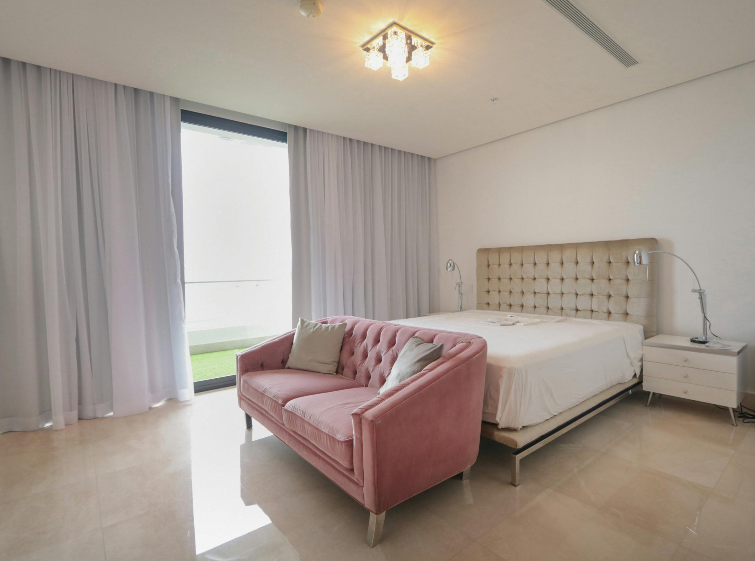 Modern bedroom design featuring a pink sofa, elegant bed, and soft lighting for a cozy ambiance.