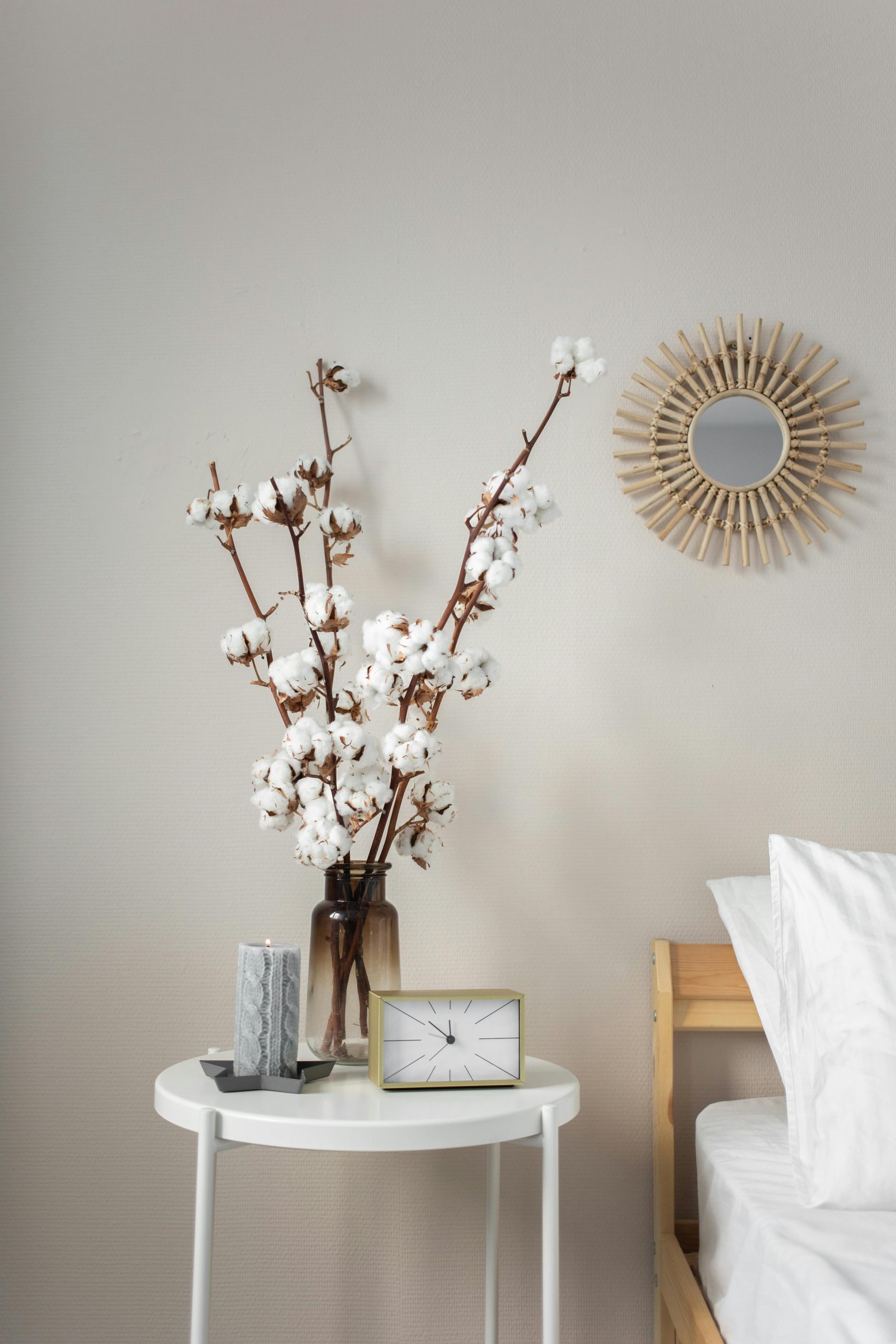 Simple and stylish bedroom corner with a white bedside table and decorative cotton plant.