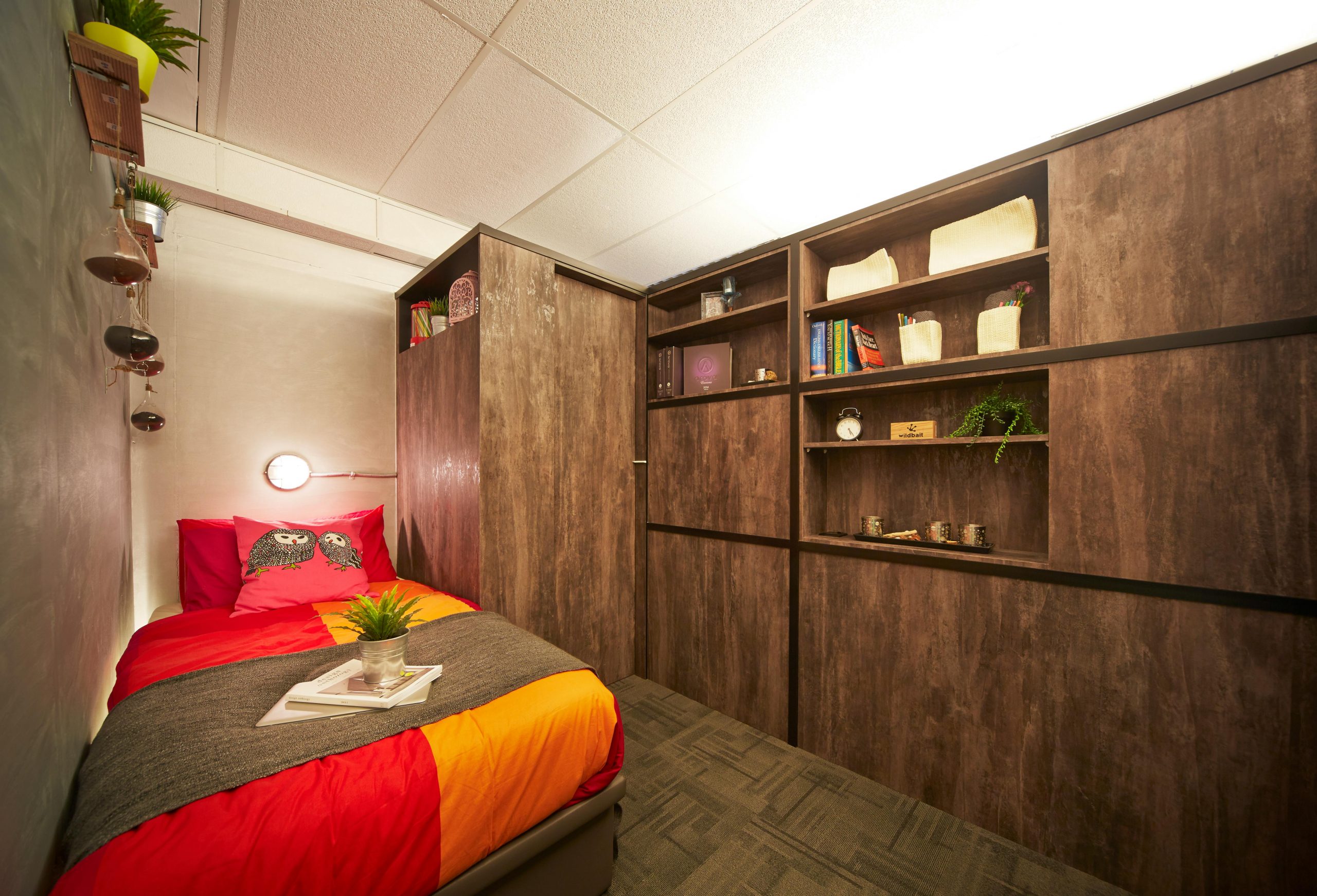 Simple bedroom interior design with colorful bed and wooden cabinet along wall in house
