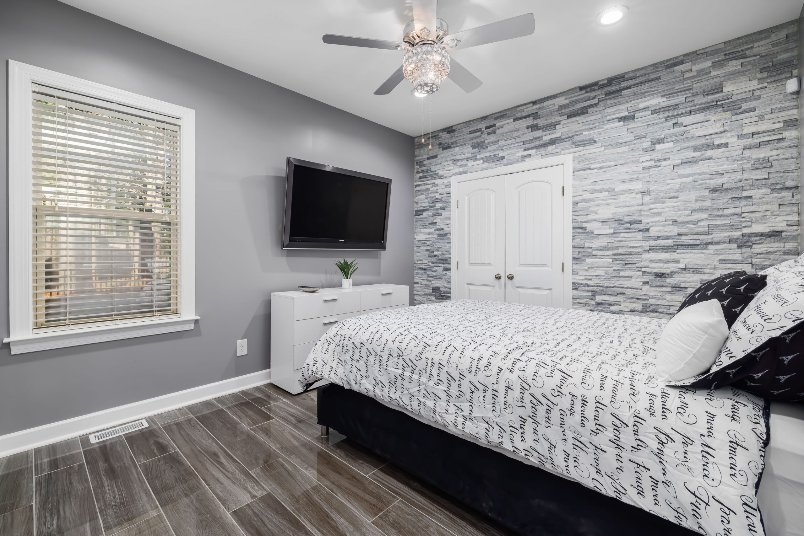 Sleek and cozy bedroom featuring modern design with stone accent wall and minimalist decor.