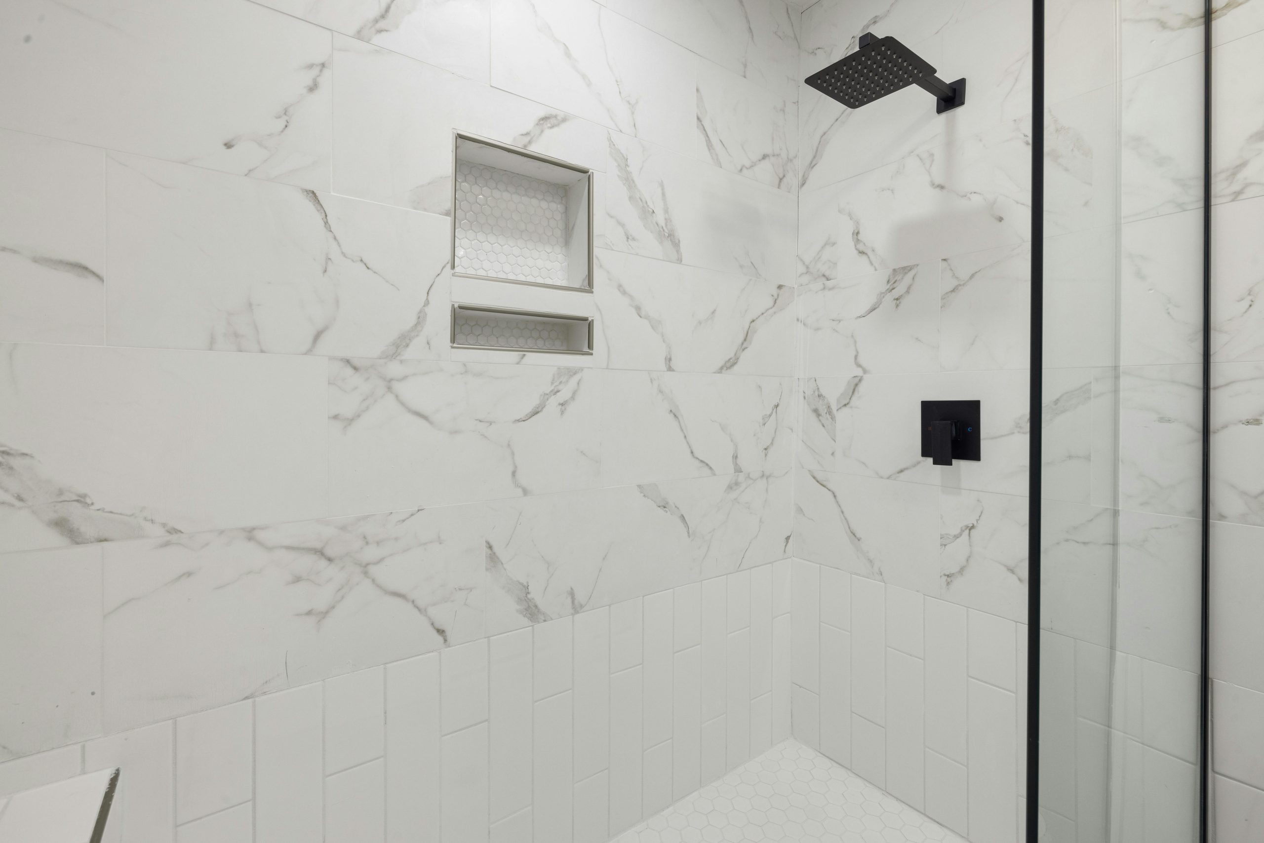Sleek bathroom shower featuring marble tiles and black fixtures, perfect for modern luxury home design.