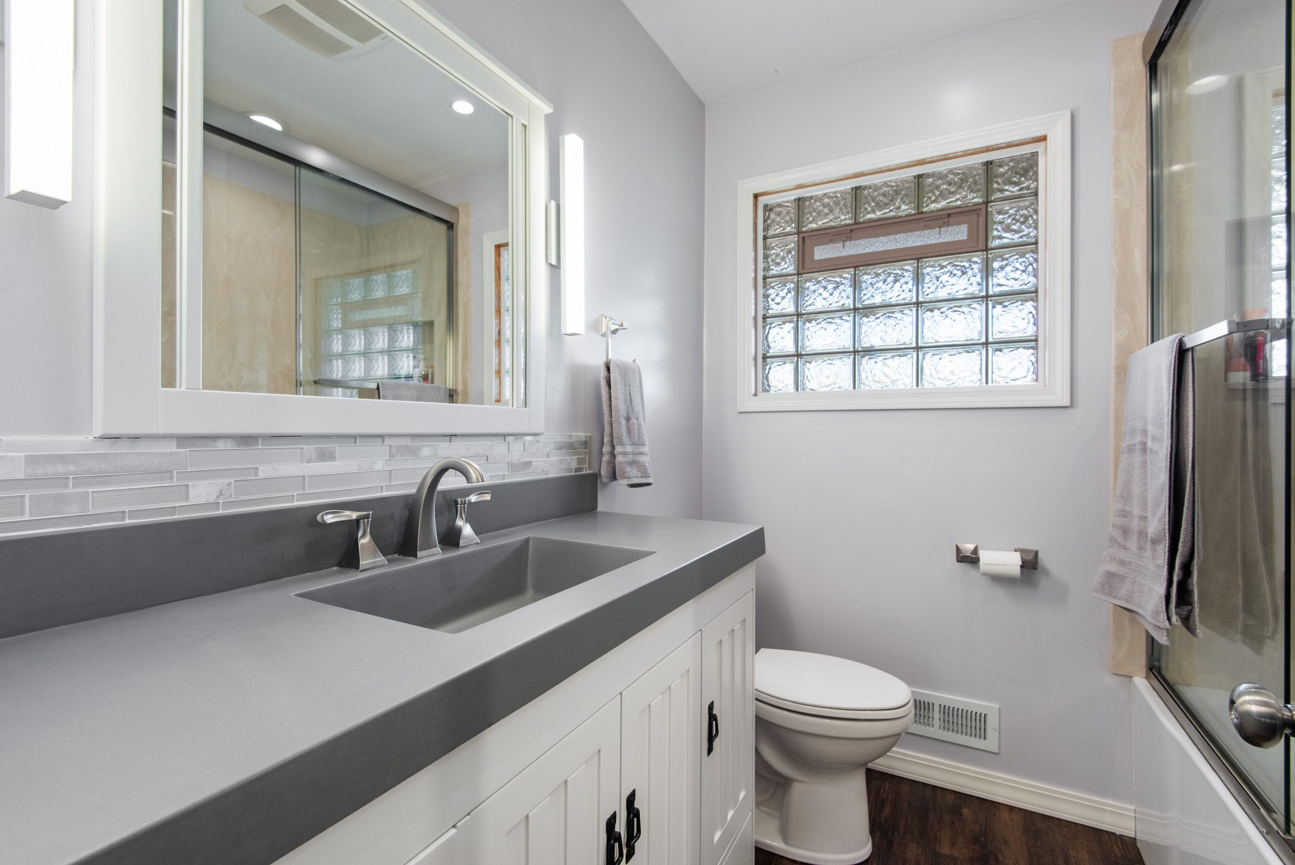 Sleek modern bathroom featuring a gray vanity, elegant mirror, and glass shower door.