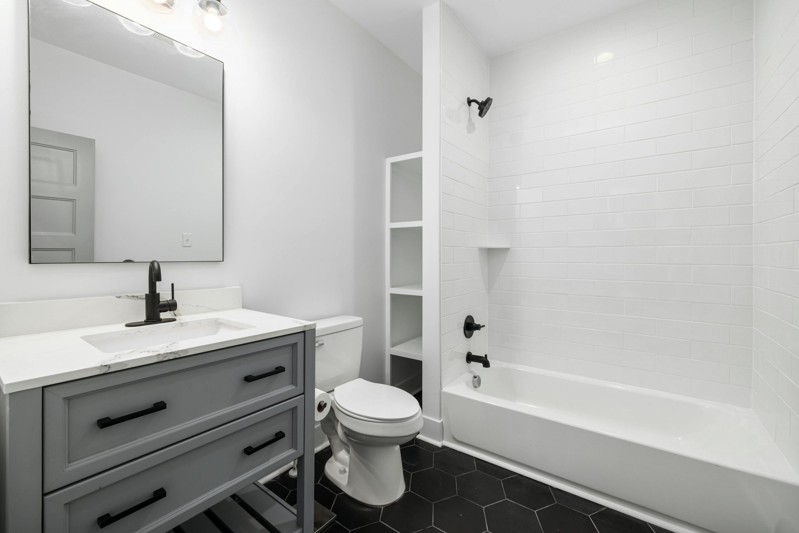 Sleek modern bathroom featuring a white bathtub, sink, toilet, and elegant fixtures.