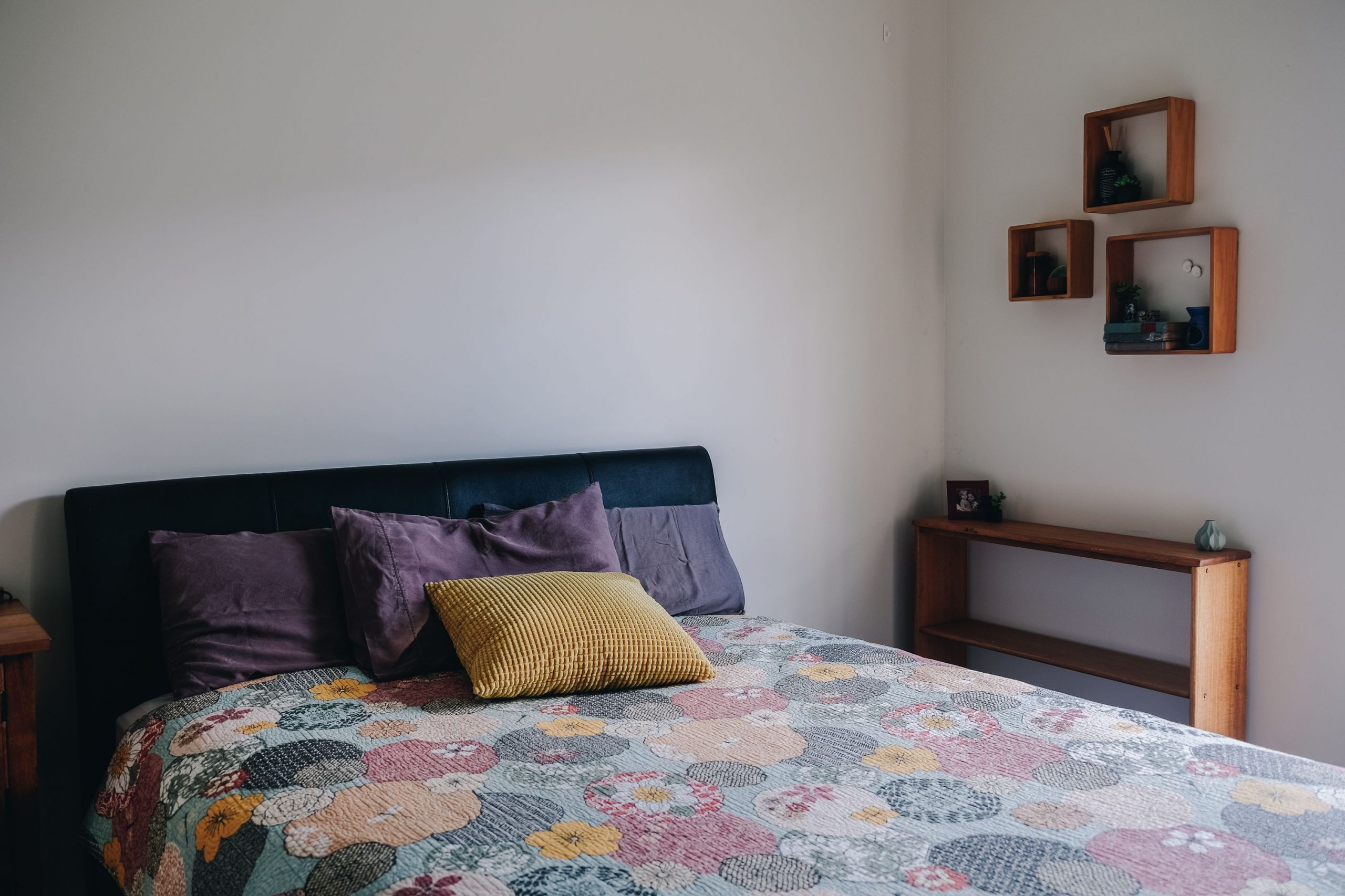 Soft pillows placed on comfortable bed with minimalist interior and wooden shelves in morning