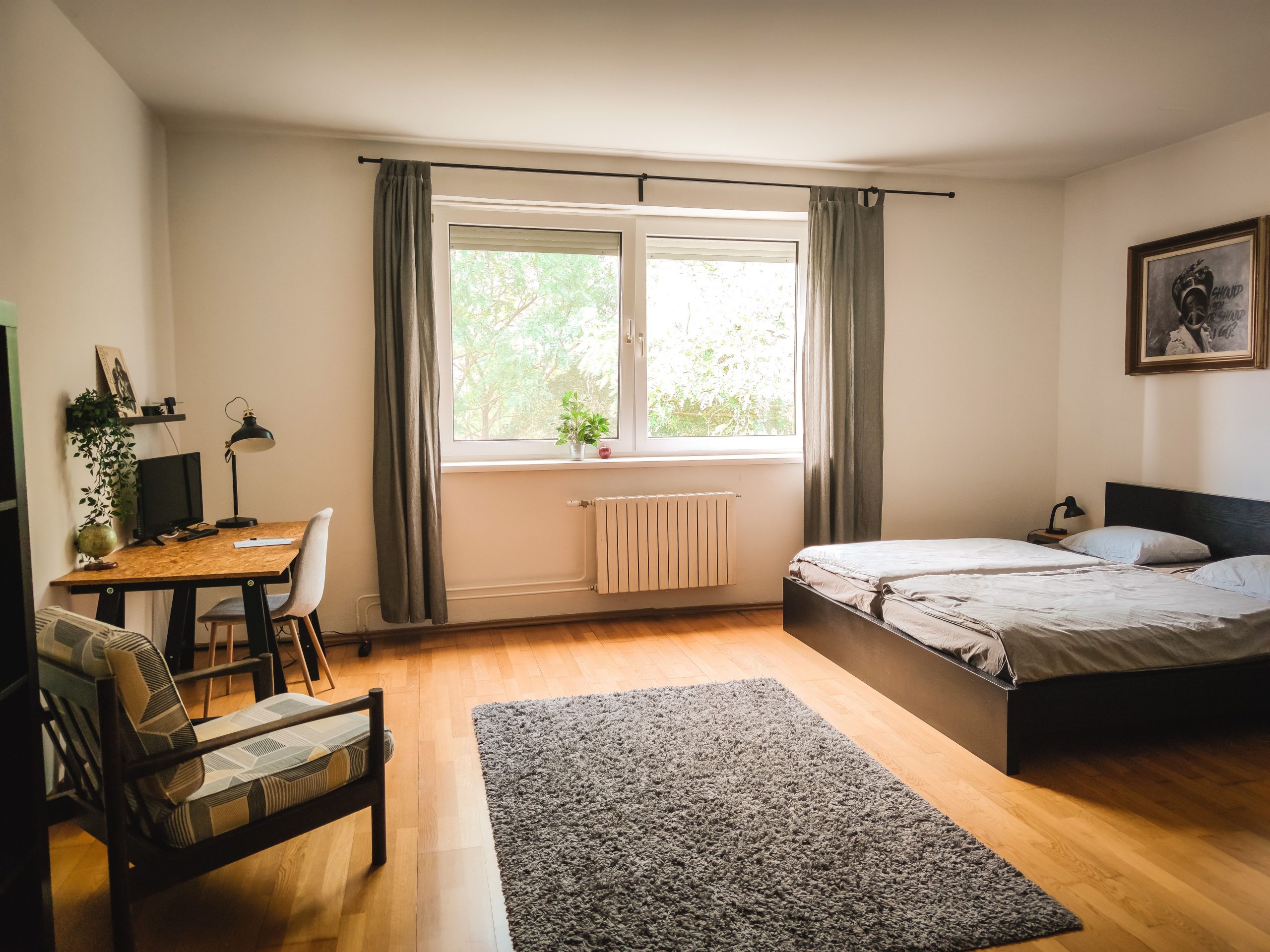 Spacious bedroom with modern decor, wooden floors, and natural light in Bratislava.