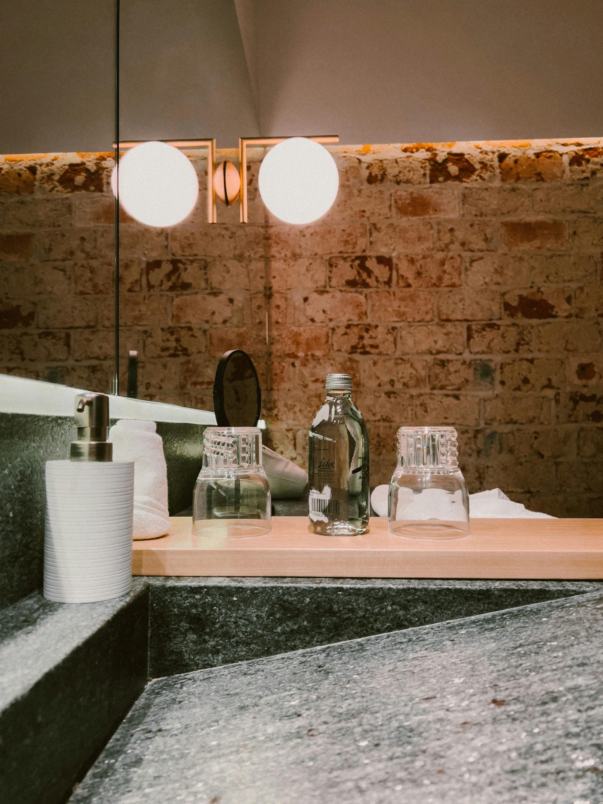 Stylish bathroom vanity with brick wall, mirror, and decor accents.