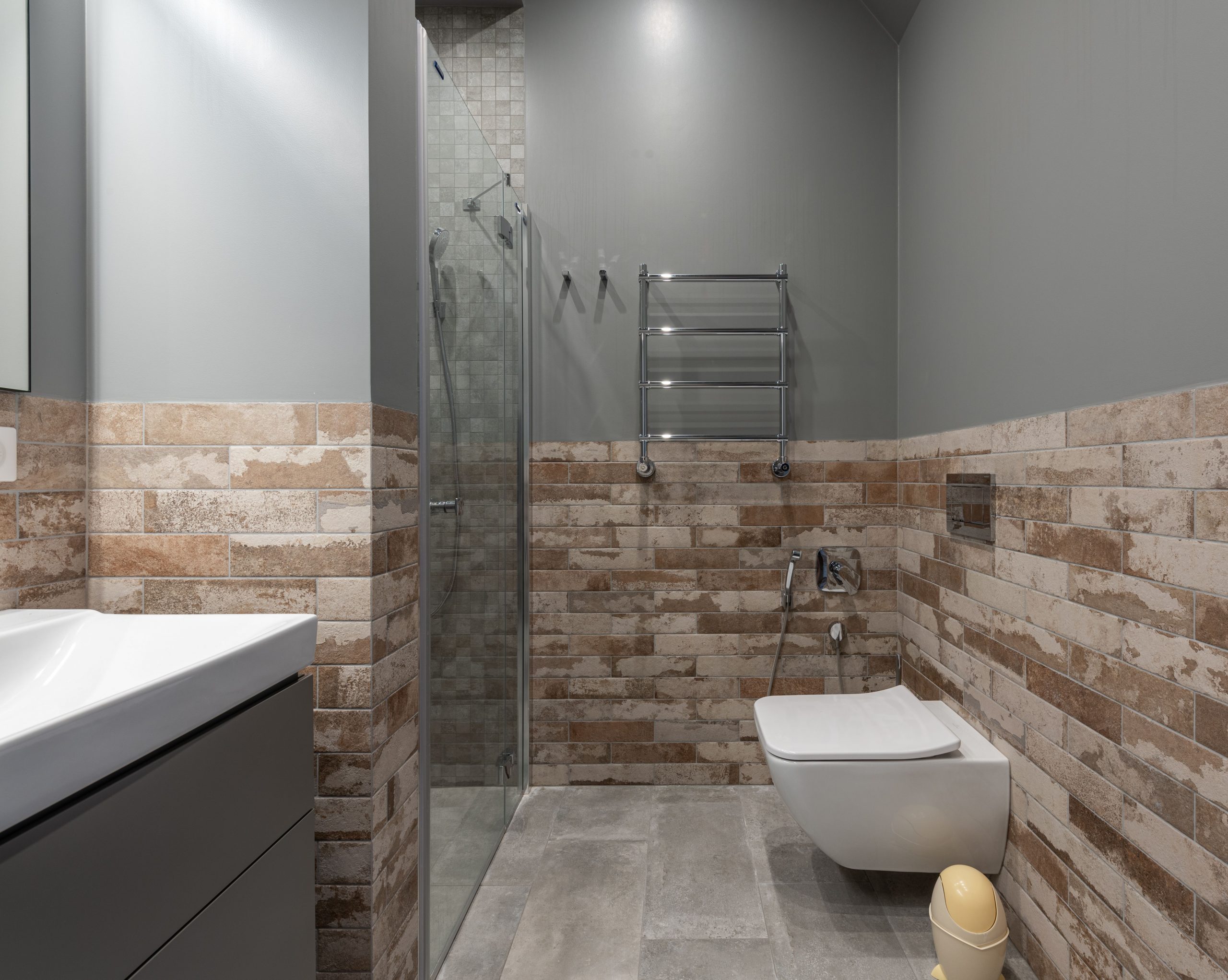 Stylish contemporary bathroom featuring a glass shower and brick accent wall.