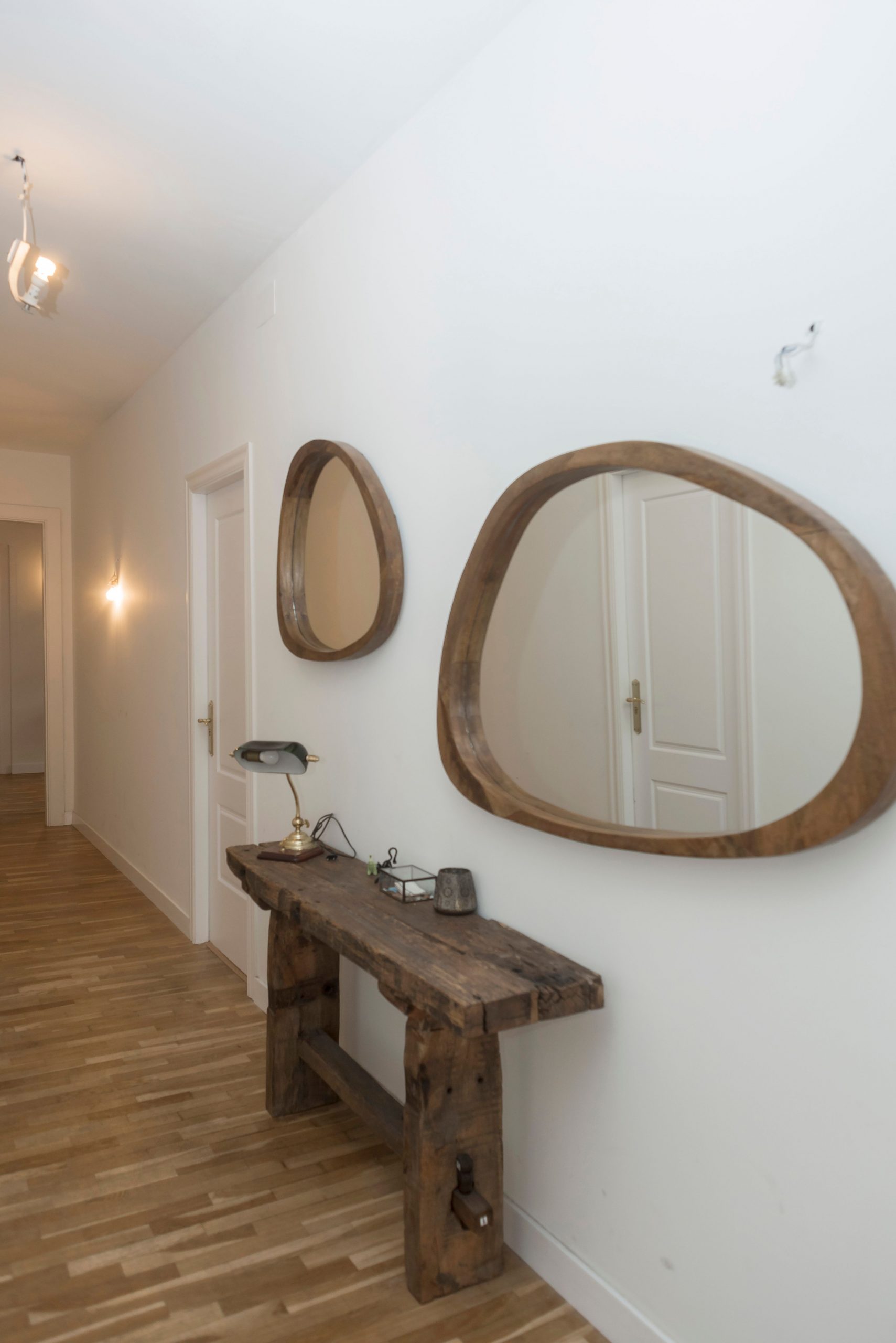 Stylish hallway with wooden mirrors and console table on white walls.