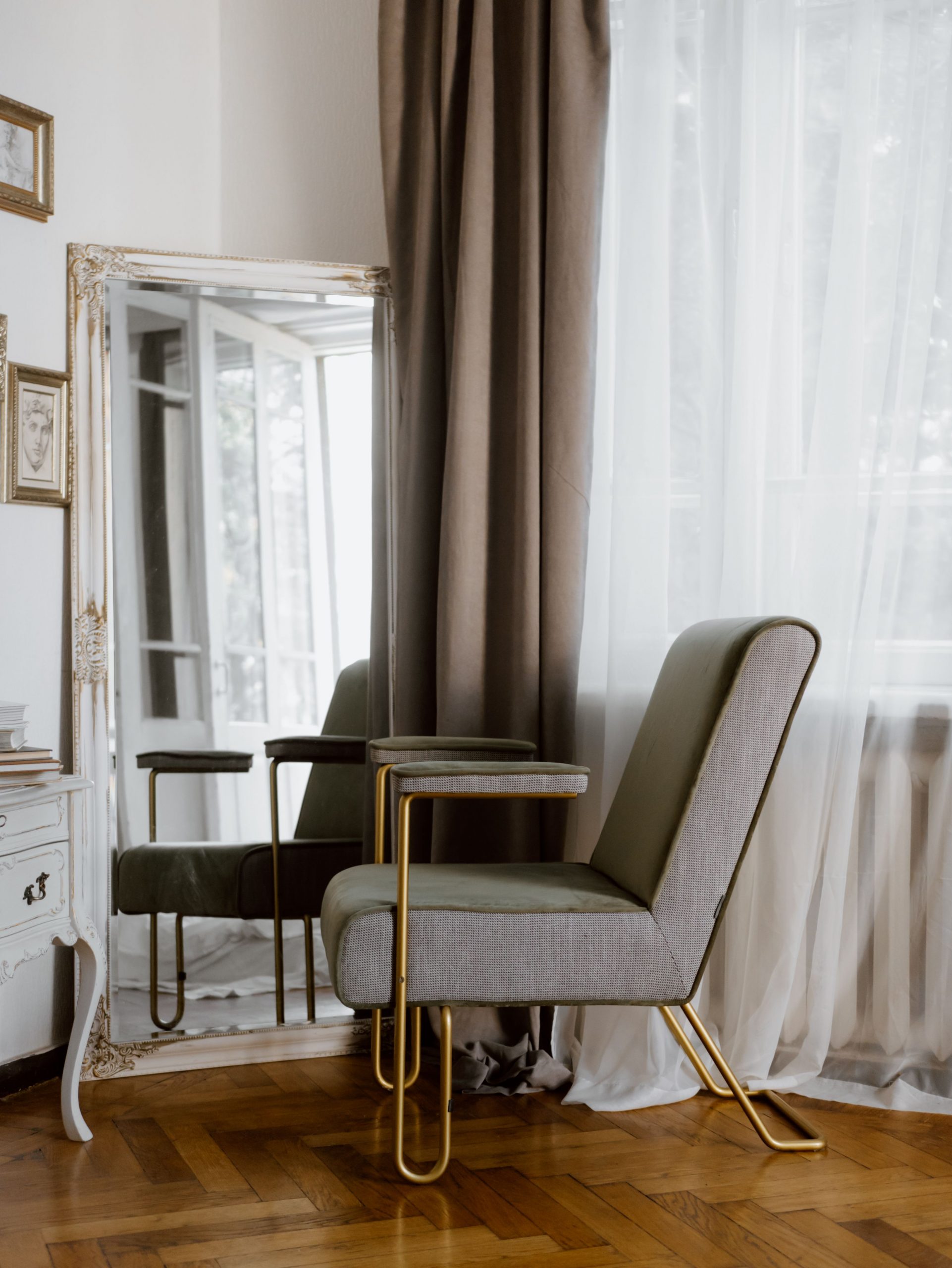 Stylish living room corner with armchair, ornate mirror, and wooden flooring.