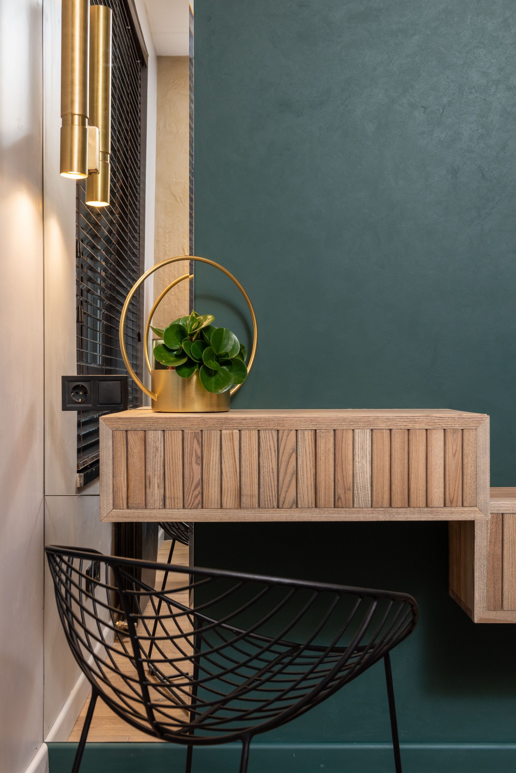 Stylish modern interior design featuring a chic green wall, wooden vanity, and a sleek black chair.