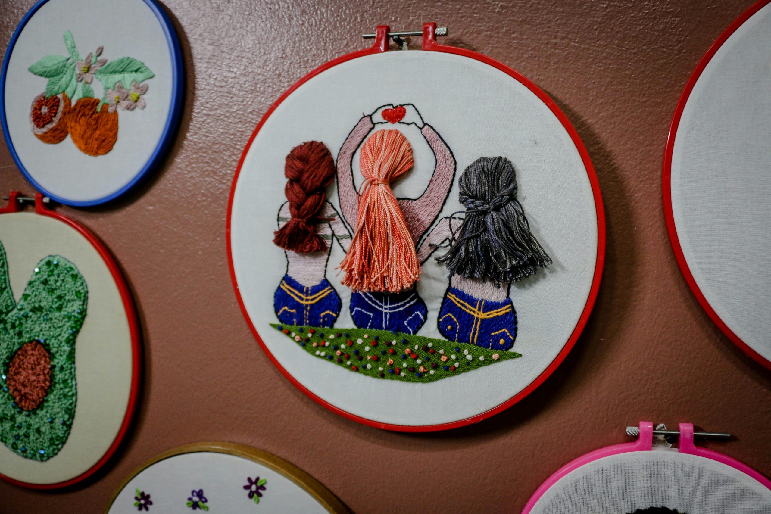 Vibrant handmade embroidery featuring artistic designs displayed on a wall.