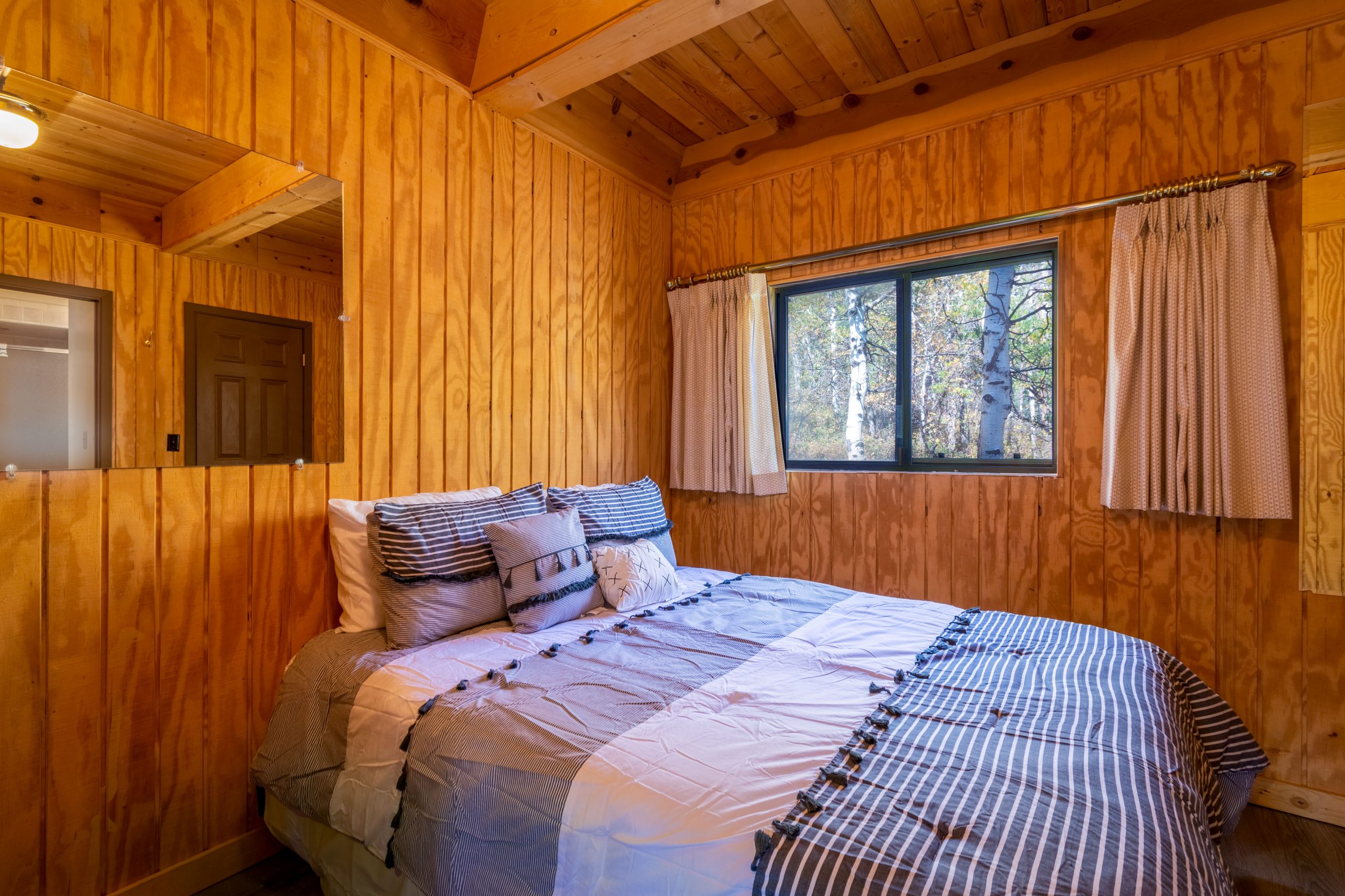 Warm and inviting wooden cabin bedroom with a comfortable bed and window view.