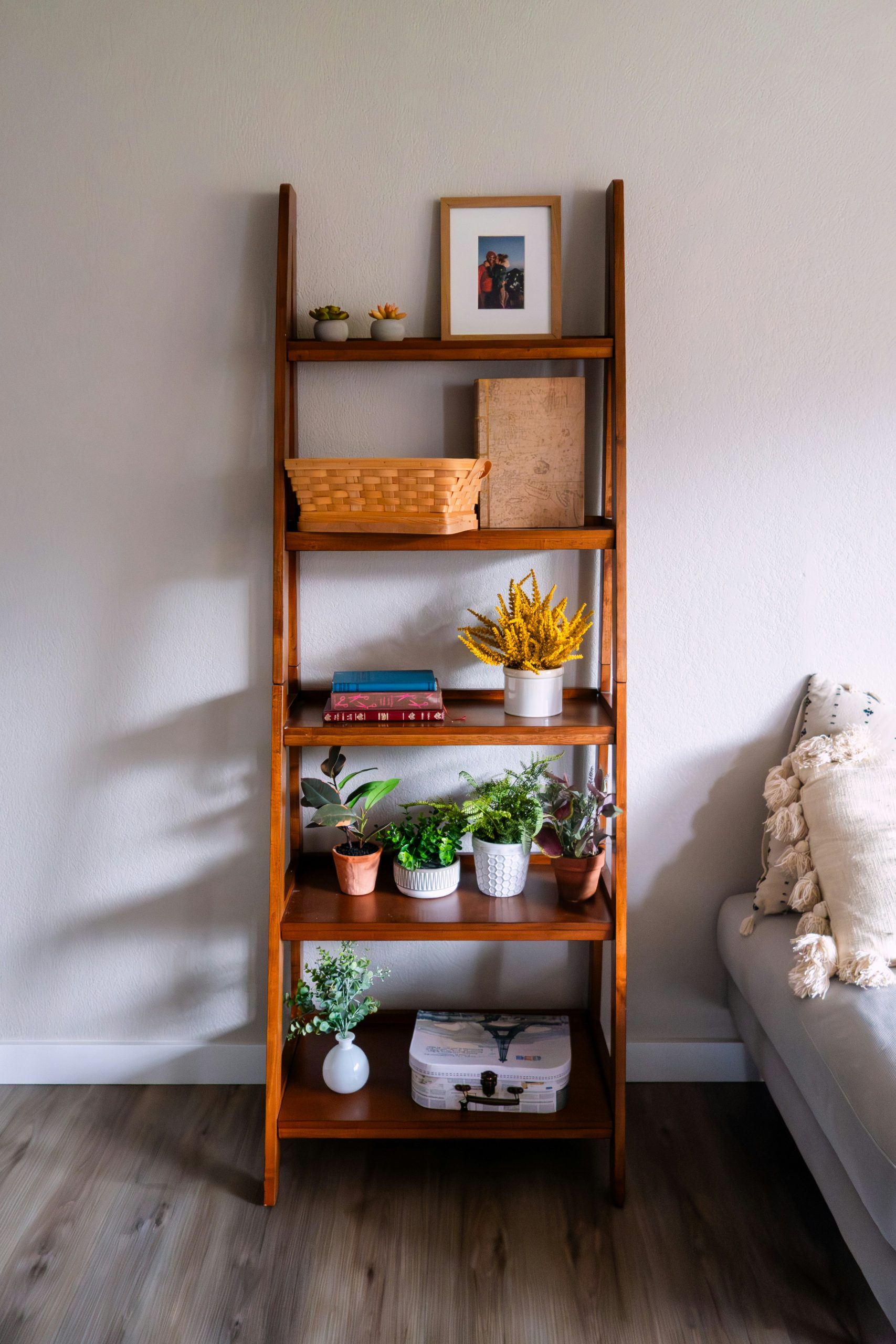 Wooden ladder shelf filled with plants and decor.