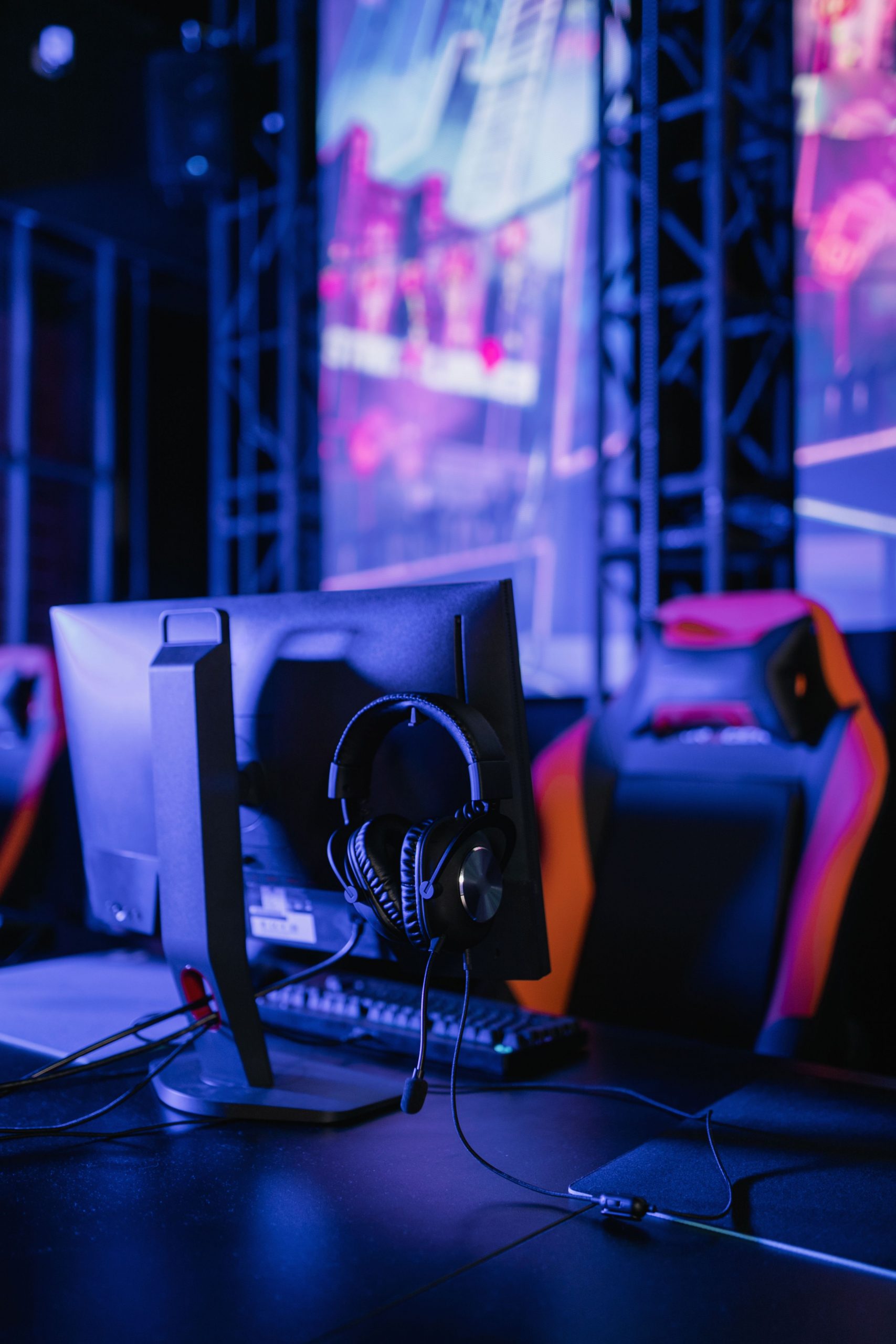 A modern gaming setup featuring a computer monitor and headset in a neon-lit environment.