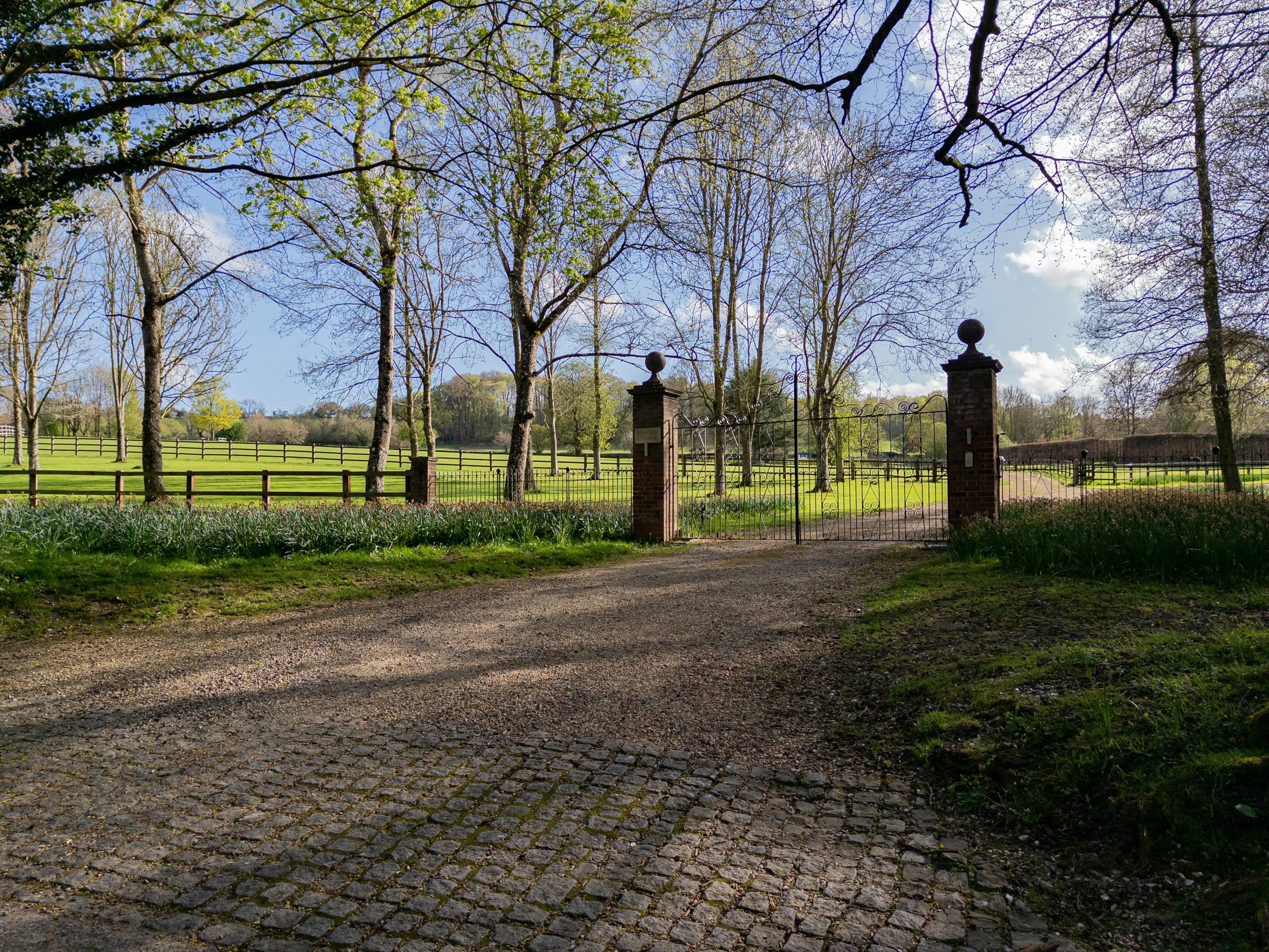 A paved driveway leads to a grand entrance with pillars.