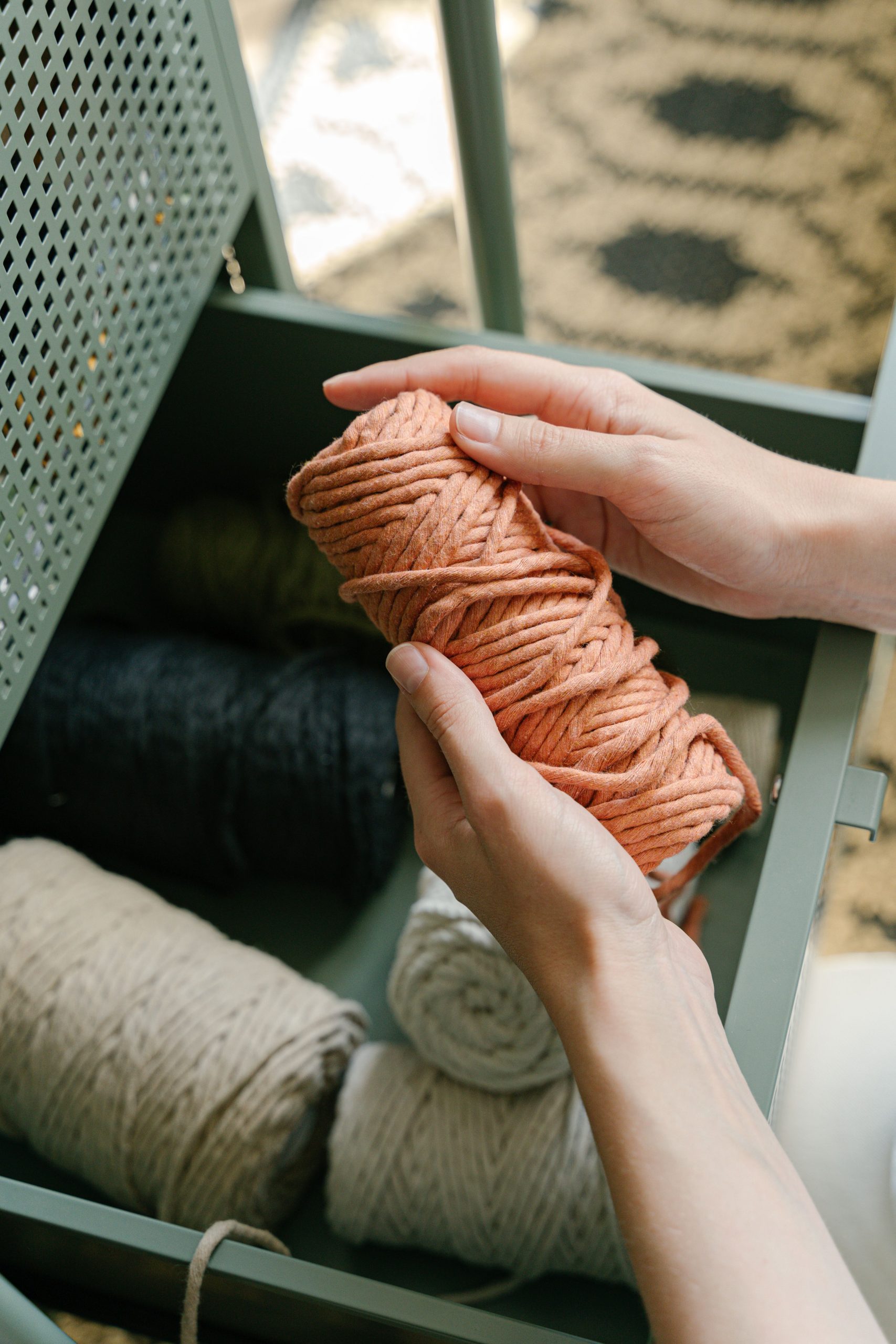 A person holds colored yarn in a drawer, perfect for craft and knitting projects.